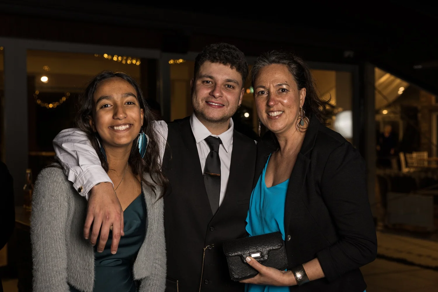 Three guests pose together at night