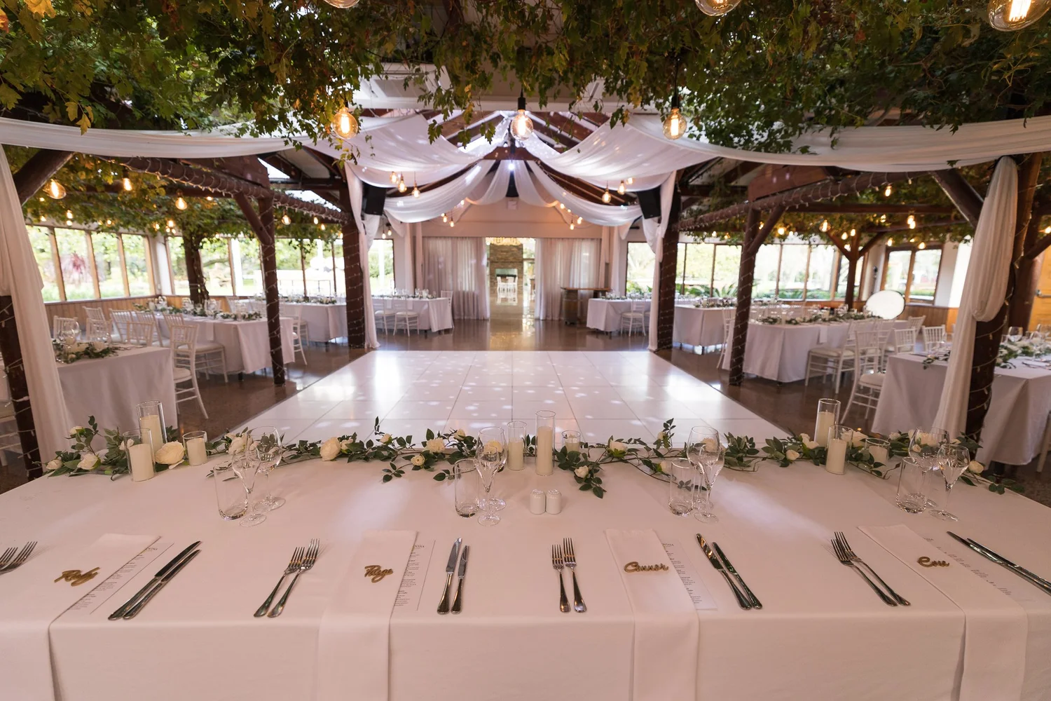 Reception tables set with white linen and greenery at Markovina Vineyard Estate