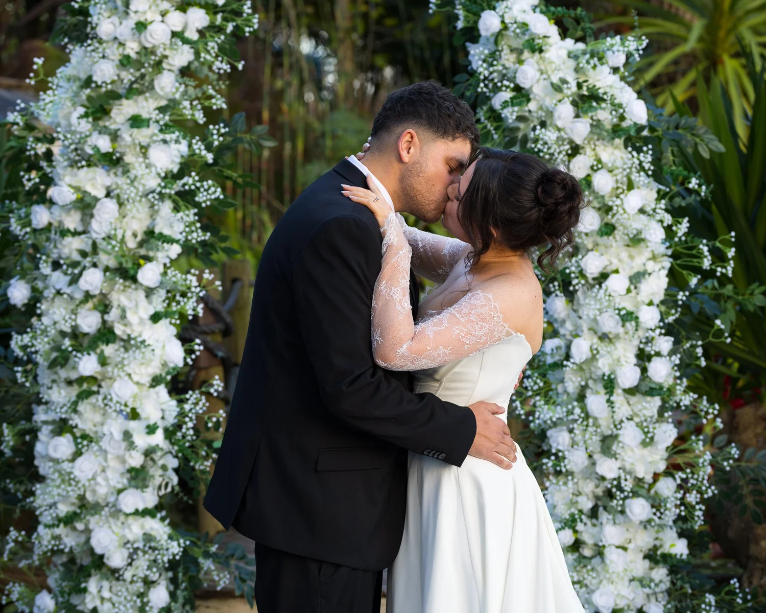 Paige and Connor's first kiss under the white floral arch