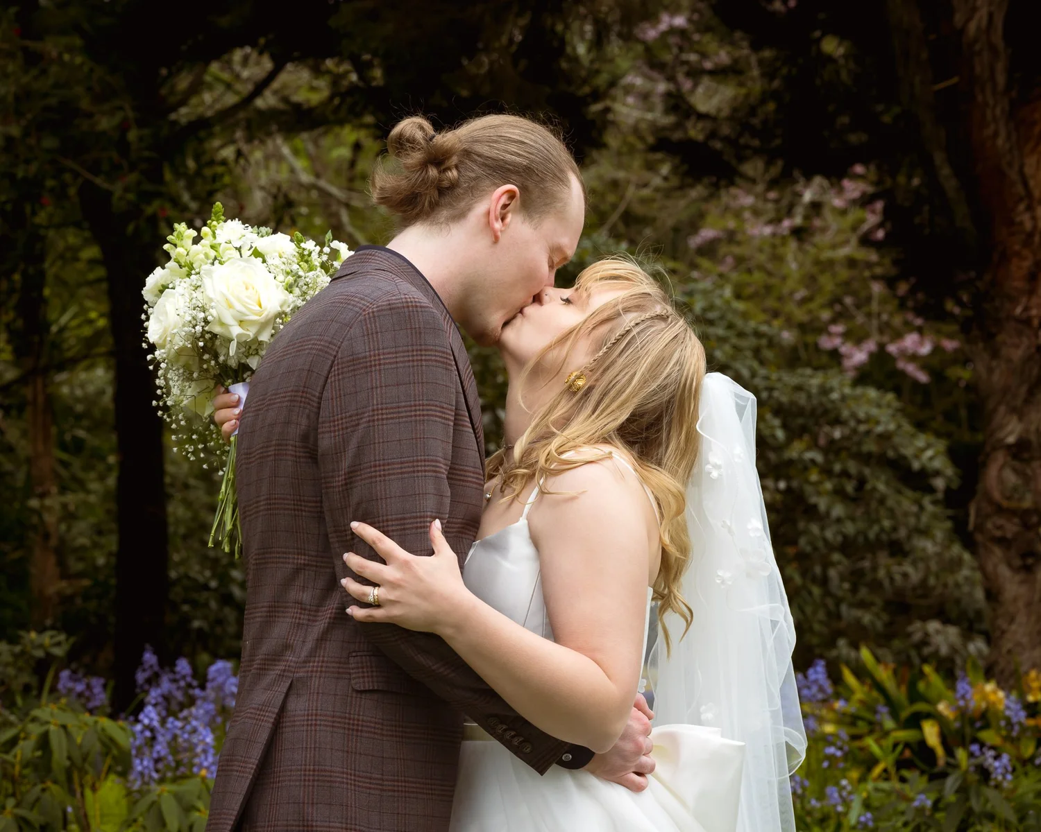 Shannon and Connor kiss in the garden with her bouquet