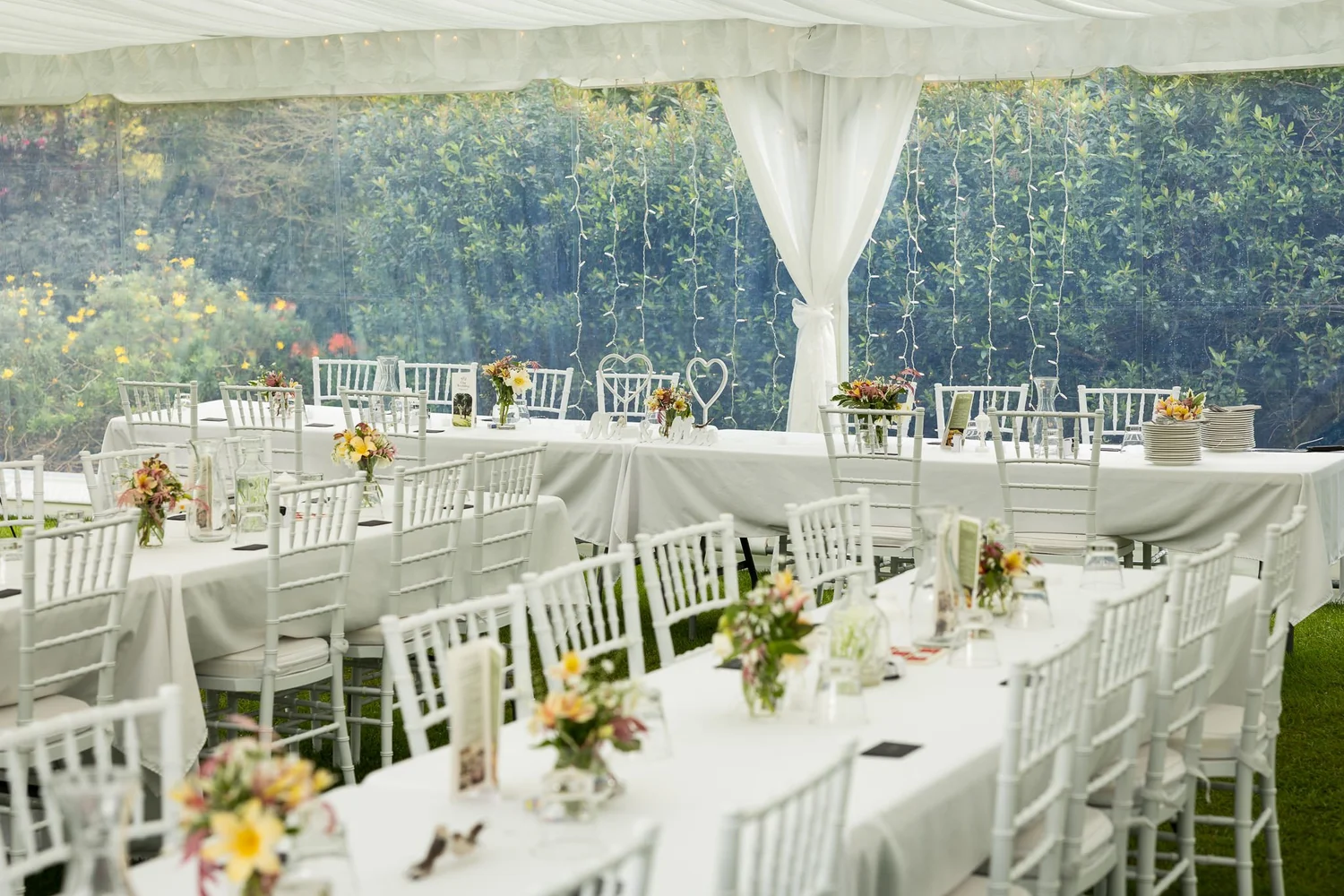 Long reception tables in a white marquee in the garden