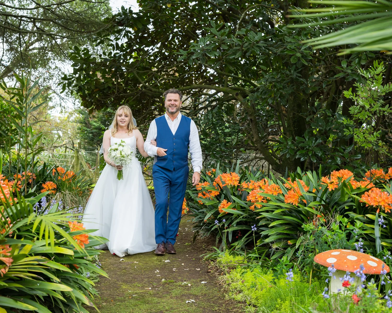Shannon is walked down the garden path among orange flowers
