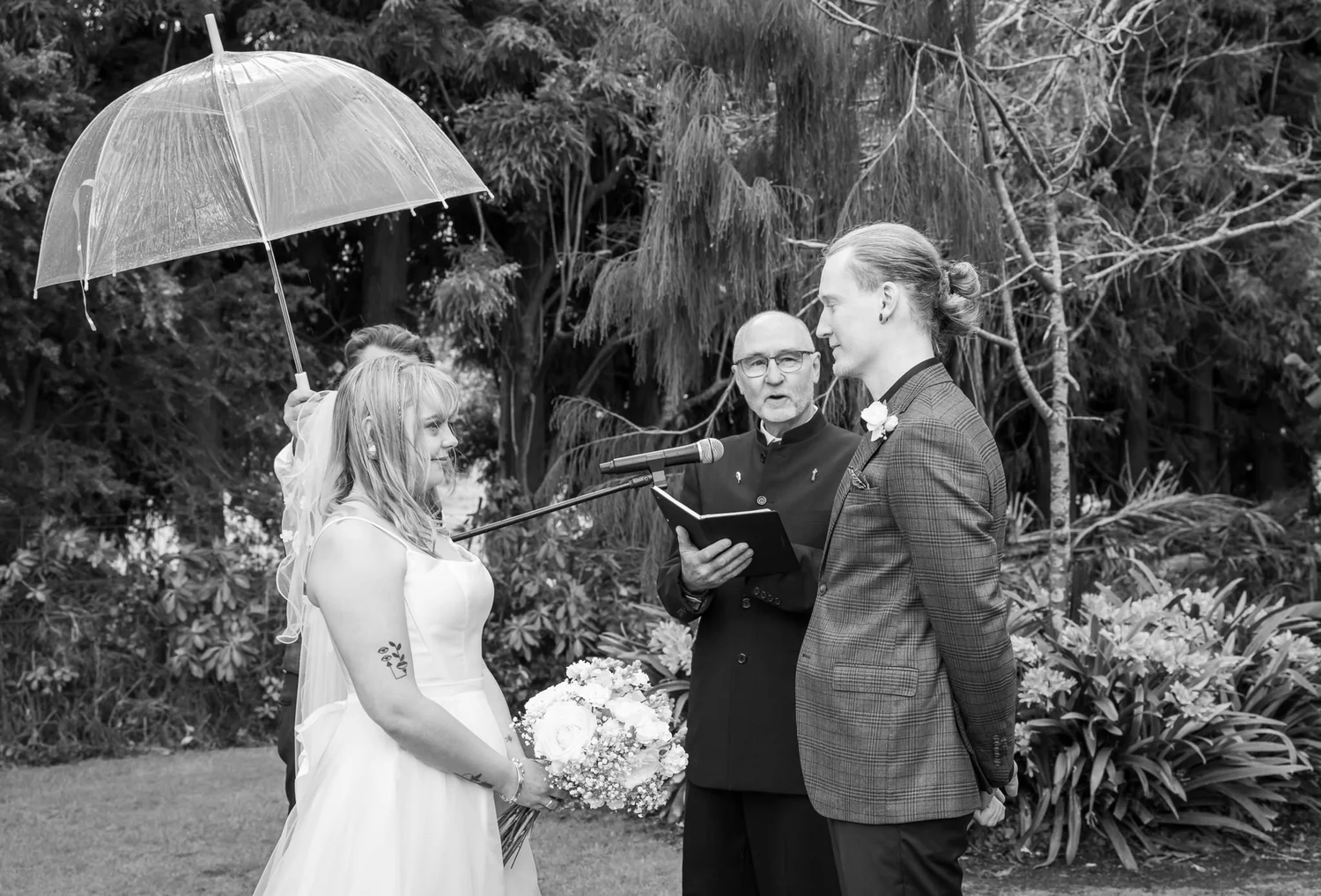 Black and white photo of the celebrant under an umbrella during the ceremony