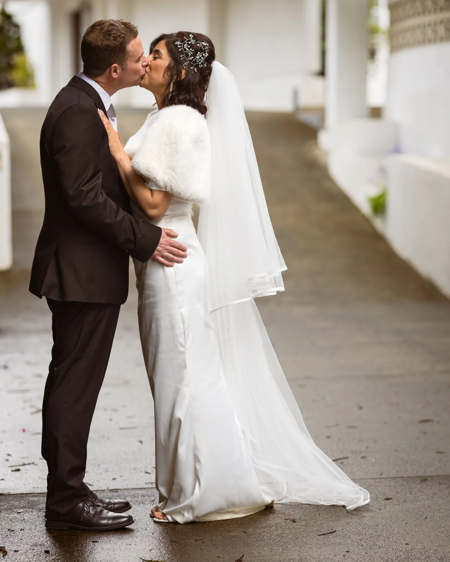 Feby and Steven kiss on the covered walkway at The Waitākere Resort and Spa