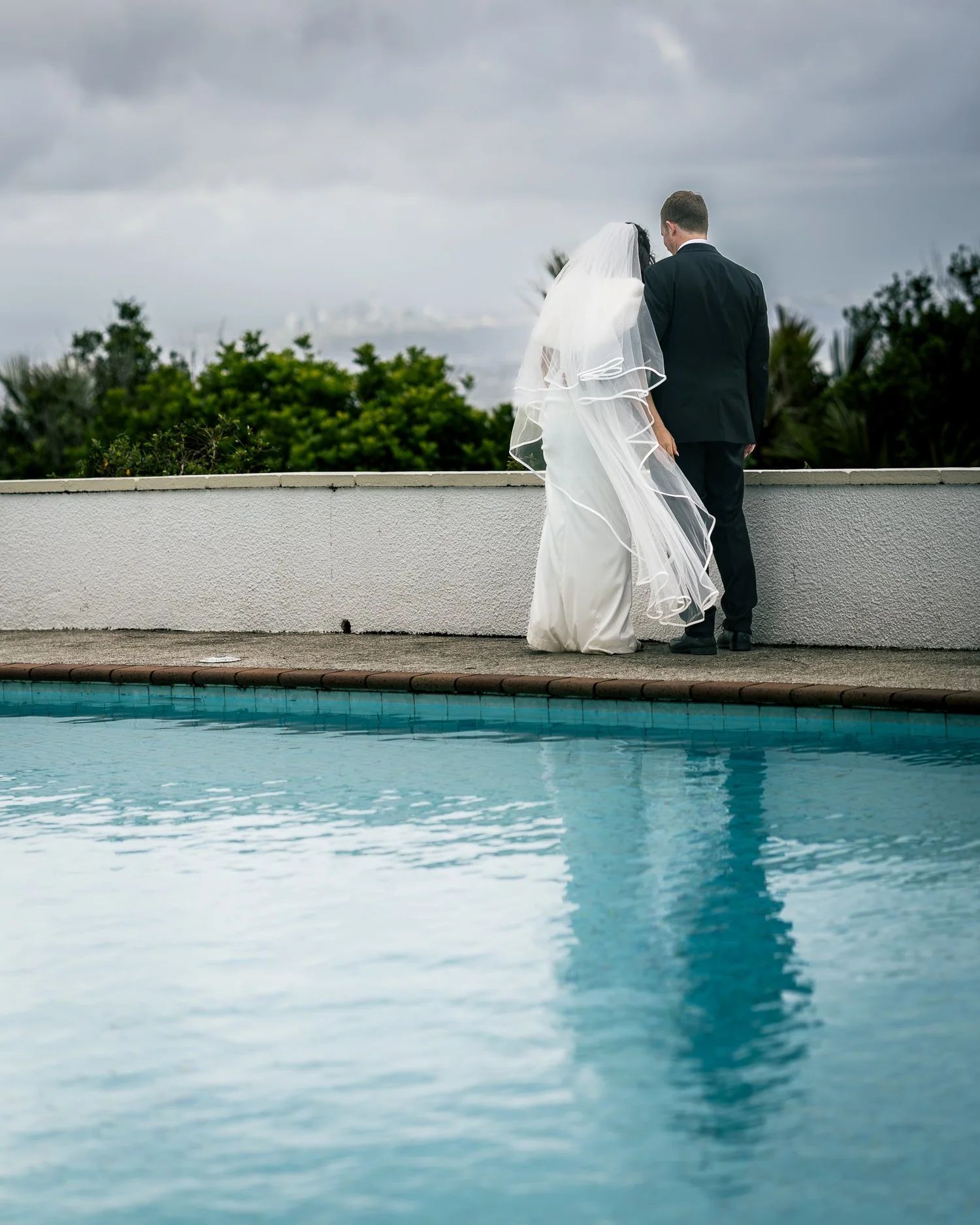 Feby and Steven stand together beside the pool