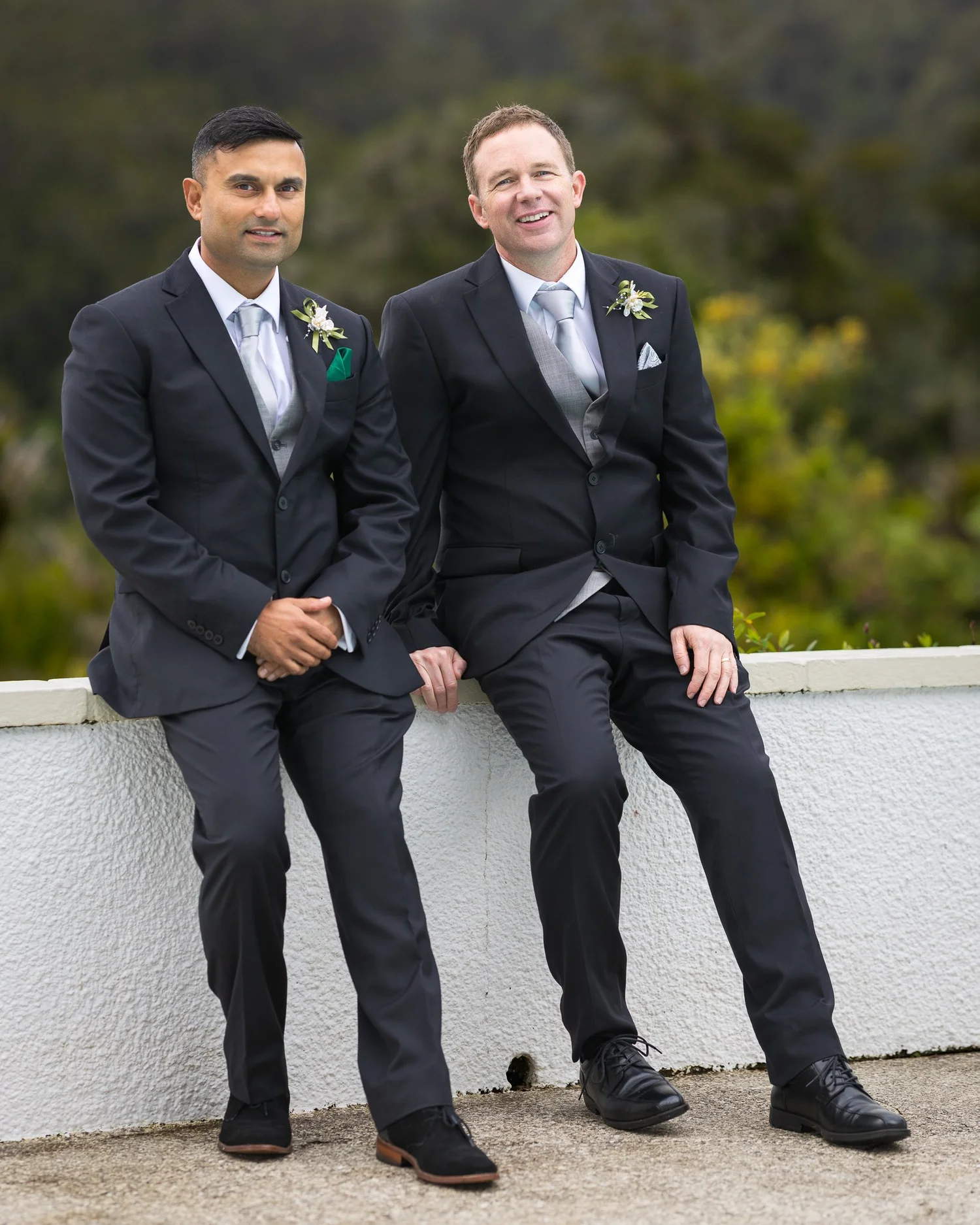 Steven and his best man sit on a white wall