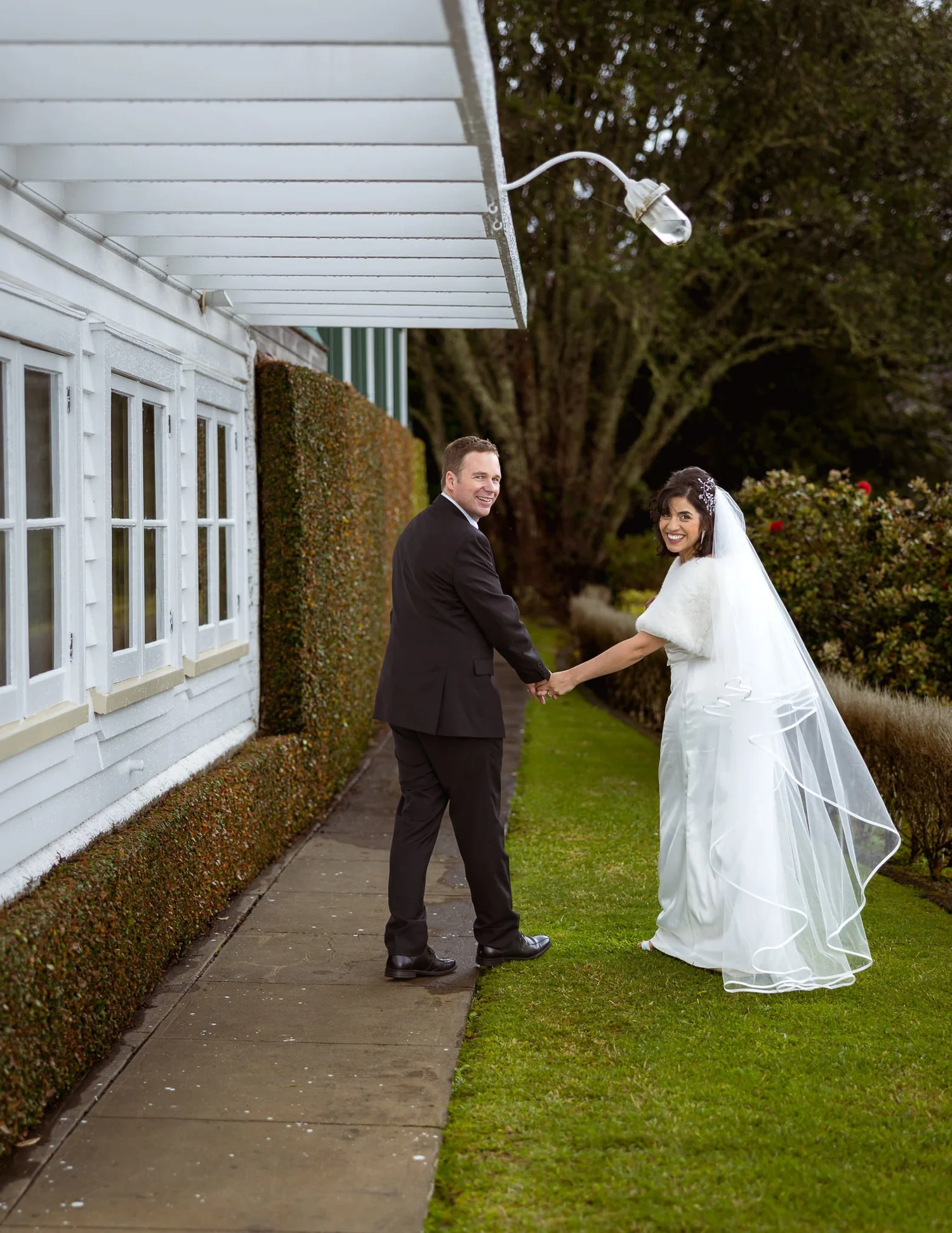 Feby and Steven walk hand in hand along a garden path