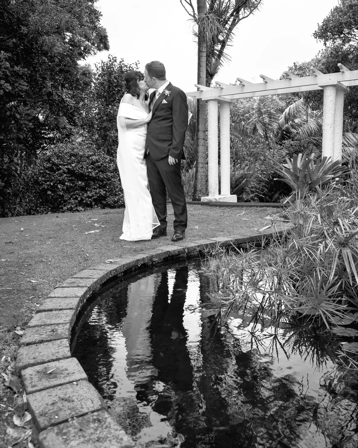 Black and white photo of Feby and Steven beside a garden pond