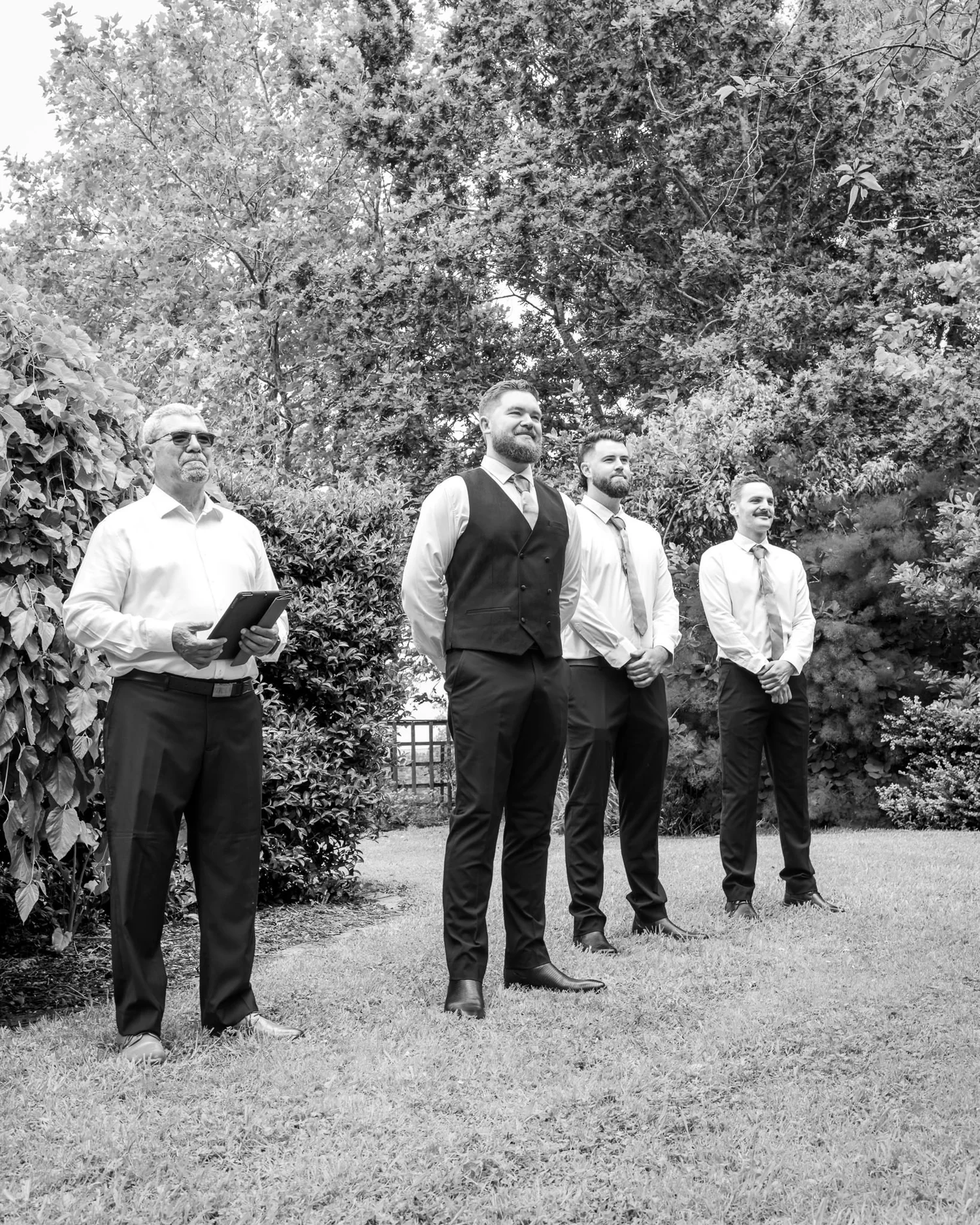 Black and white photo of Kyle and his groomsmen waiting in the garden