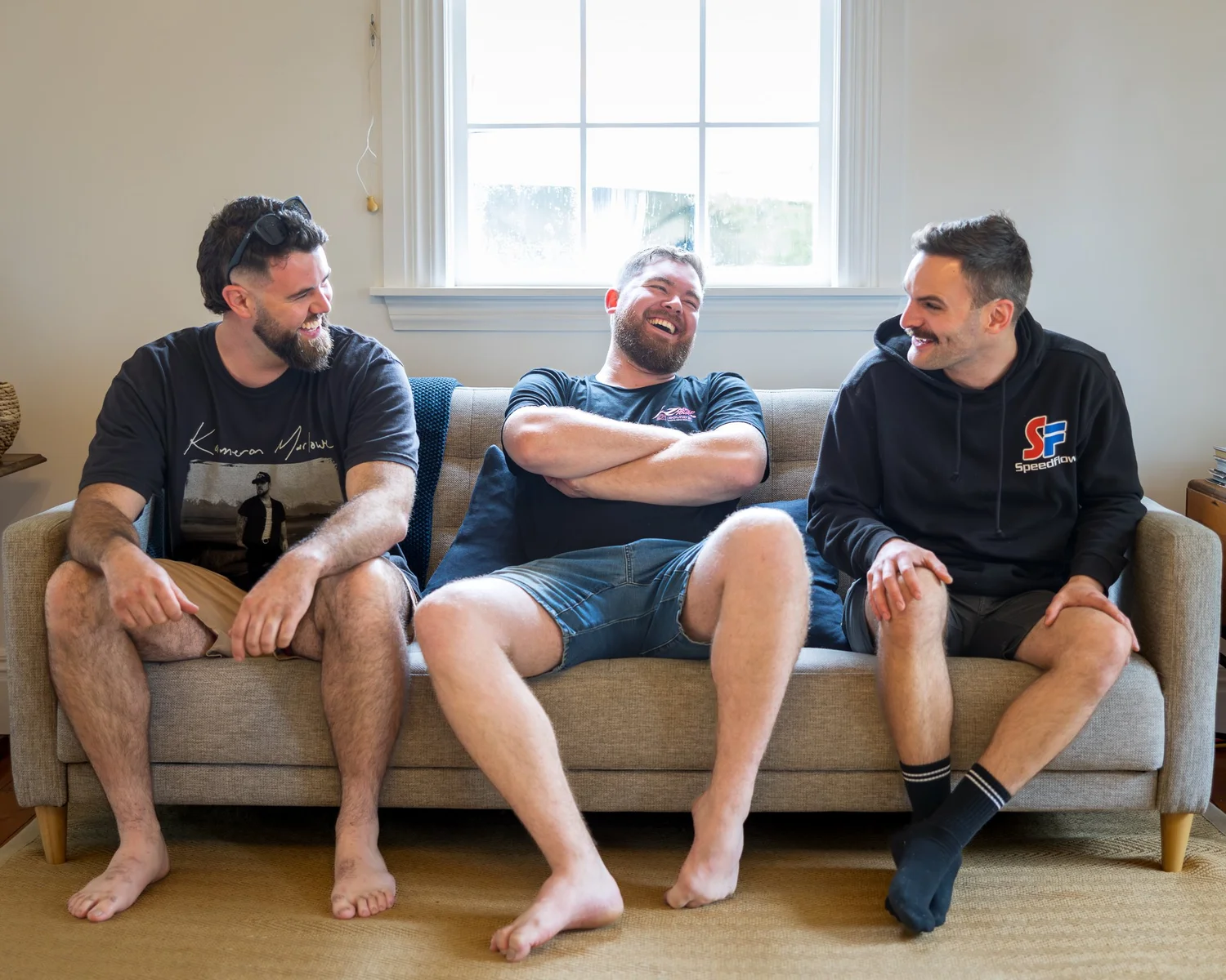 Kyle and two groomsmen relax barefoot on a sofa before the ceremony