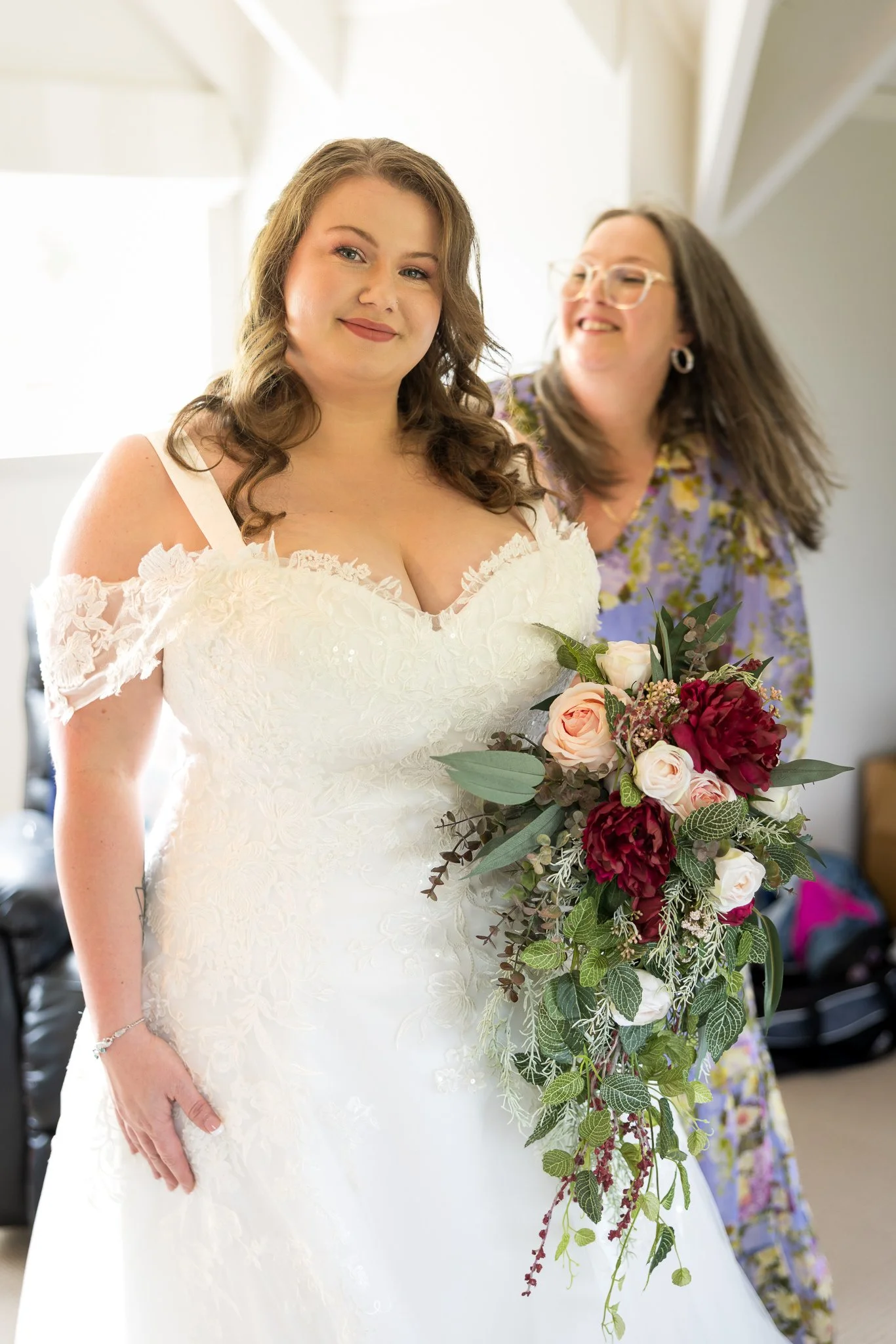 Janine holds her red and white bouquet beside a bridesmaid