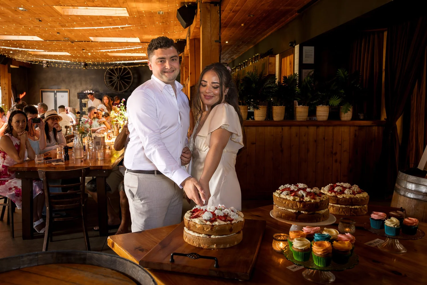 Cerise and Nick cut their cake in the restaurant at The Stables