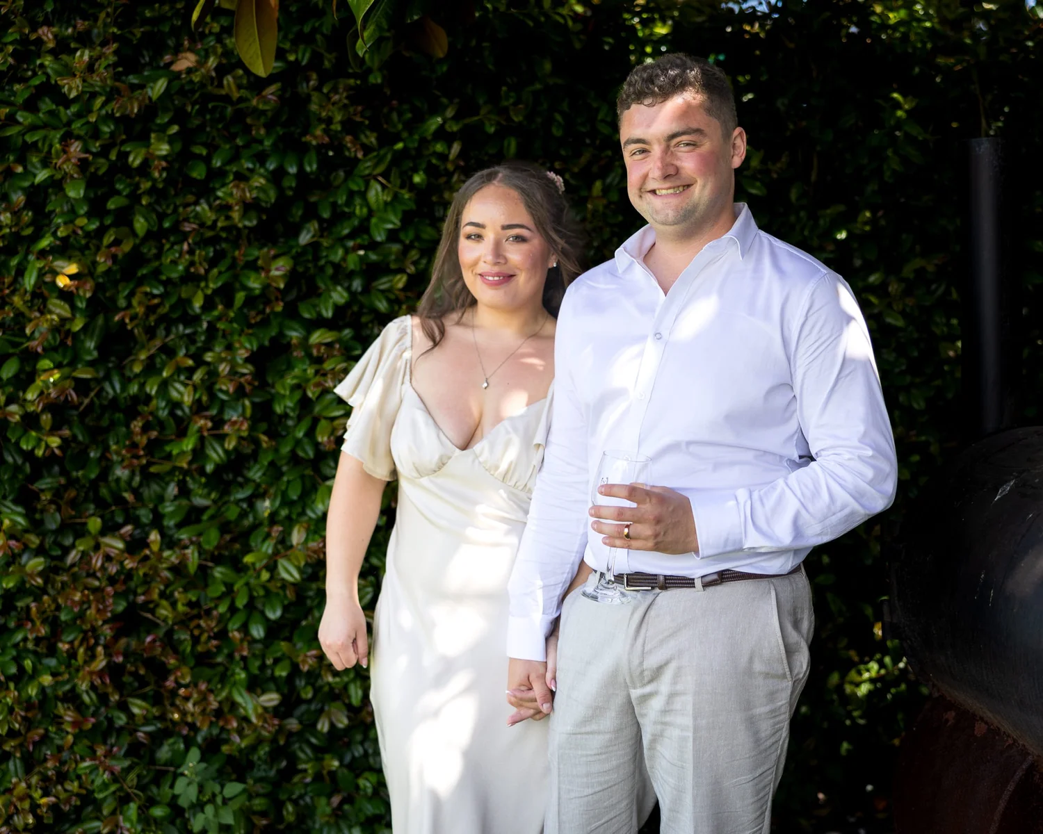 Cerise and Nick stand in front of an ivy-covered wall