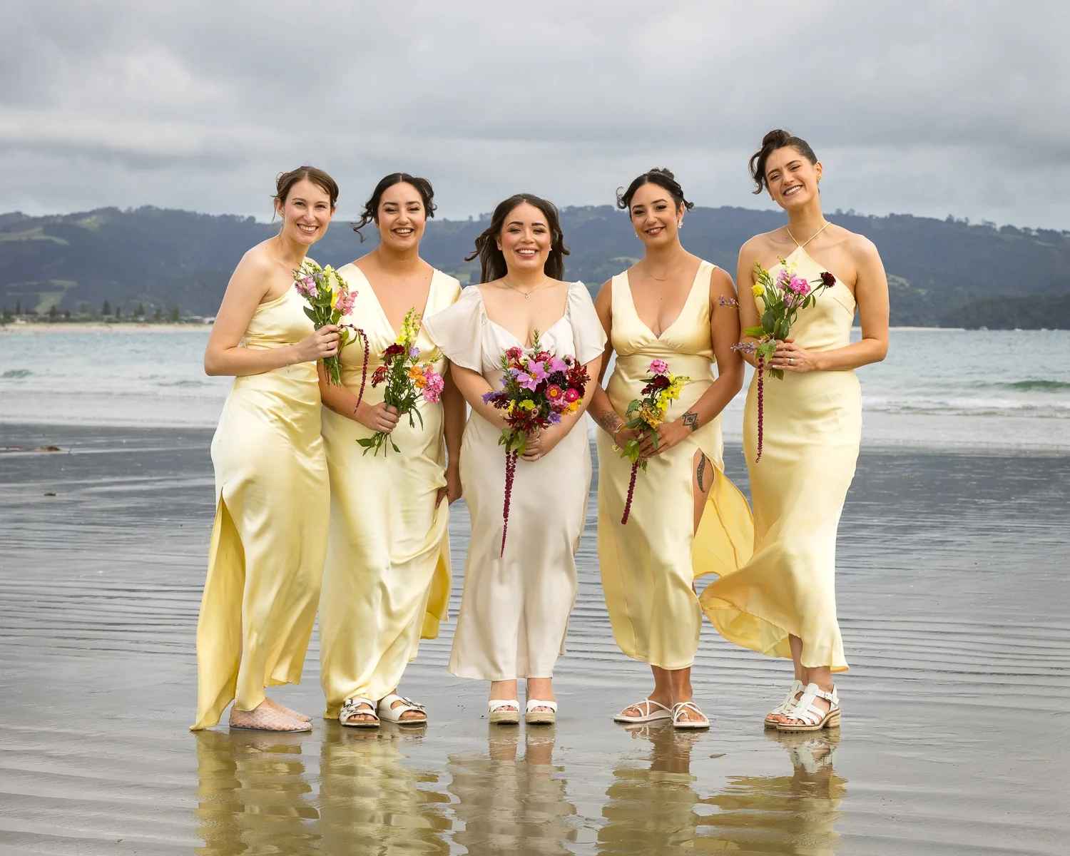 The bridesmaids in pale yellow dresses on the beach