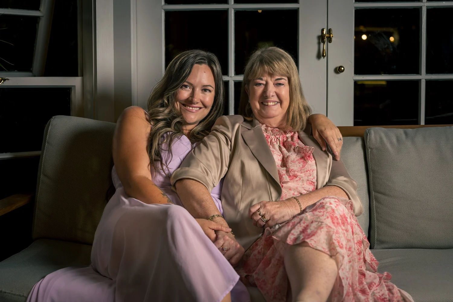 Two guests sit together on a sofa smiling
