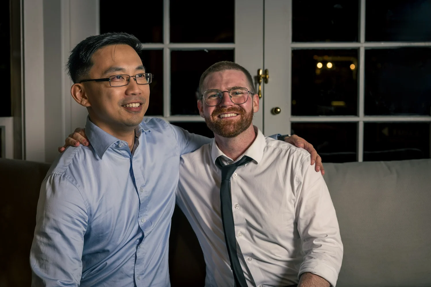 Two guests pose together on a sofa
