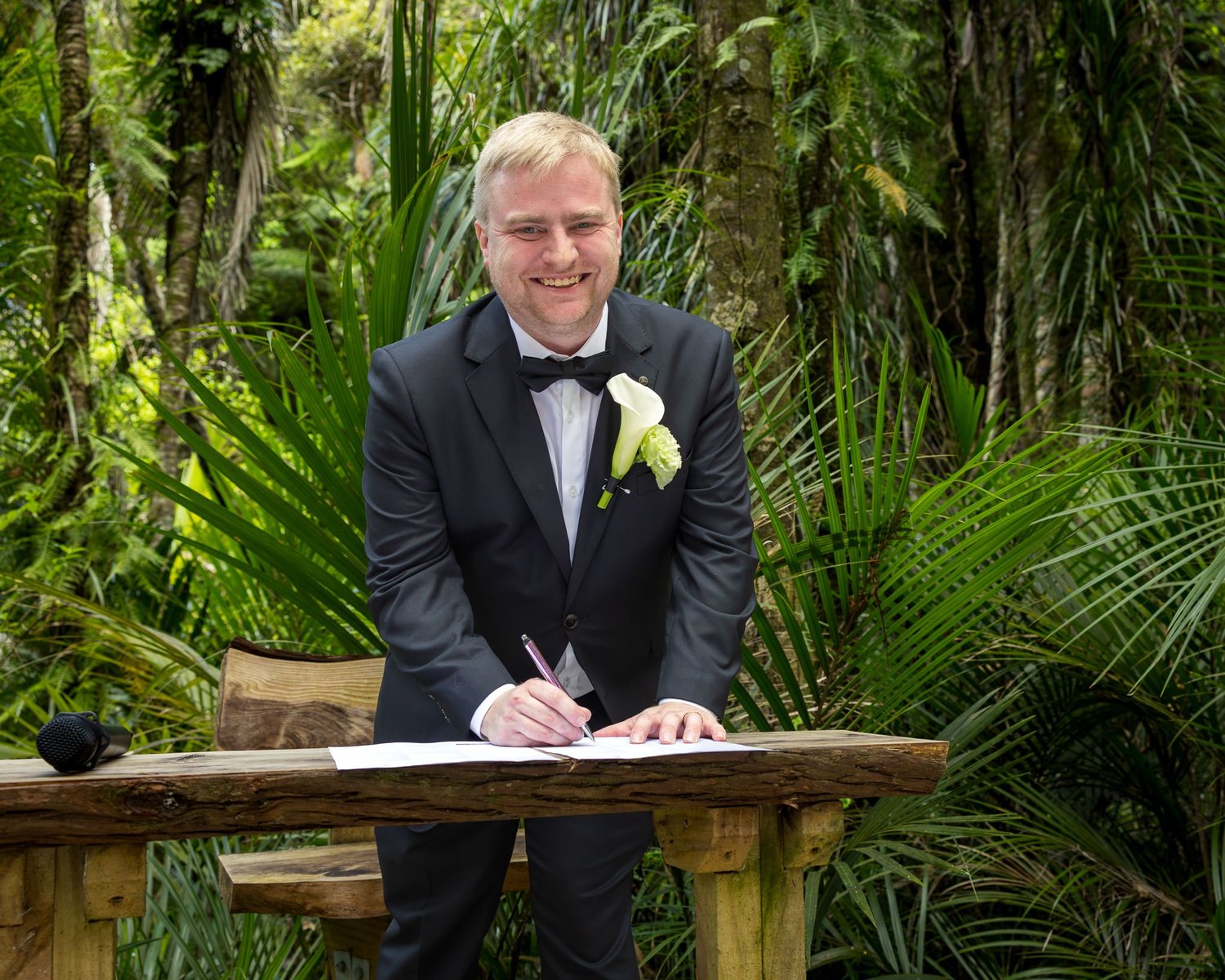 Warwick signs the wedding register at a wooden table