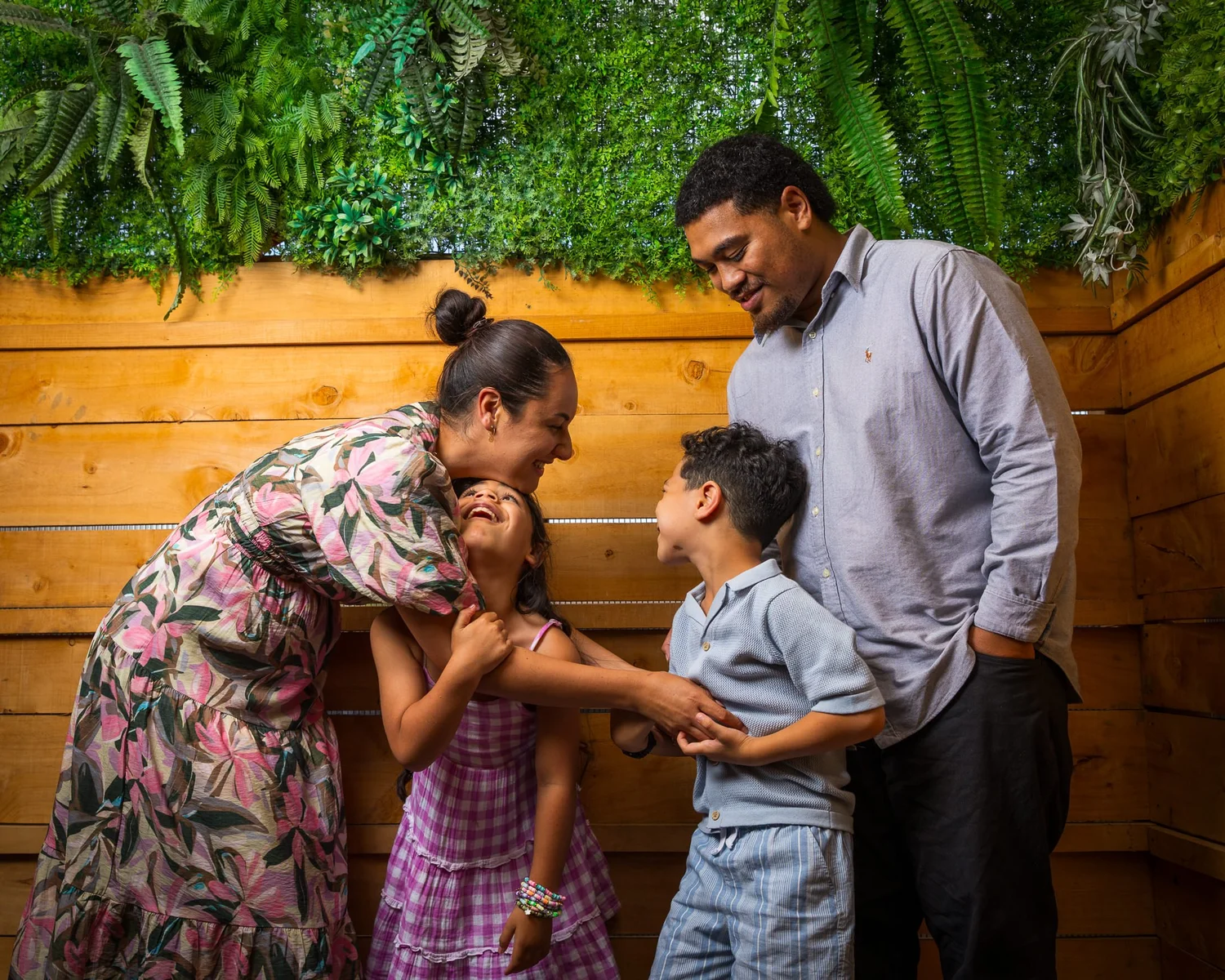 A family pose against a timber wall with a living green roof