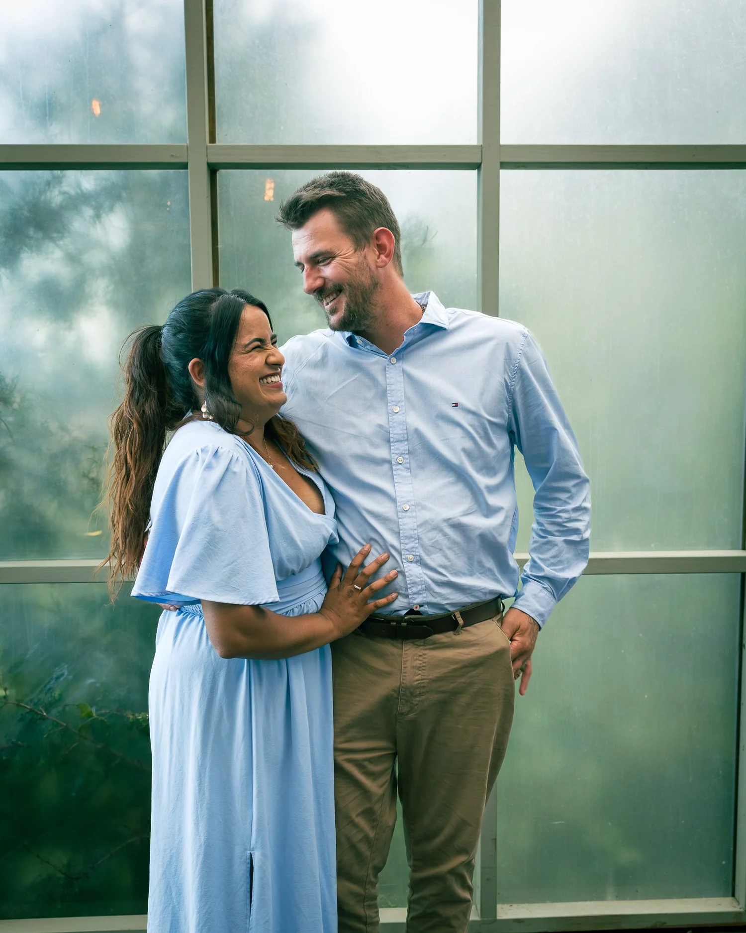 Two guests pose in front of a misty window