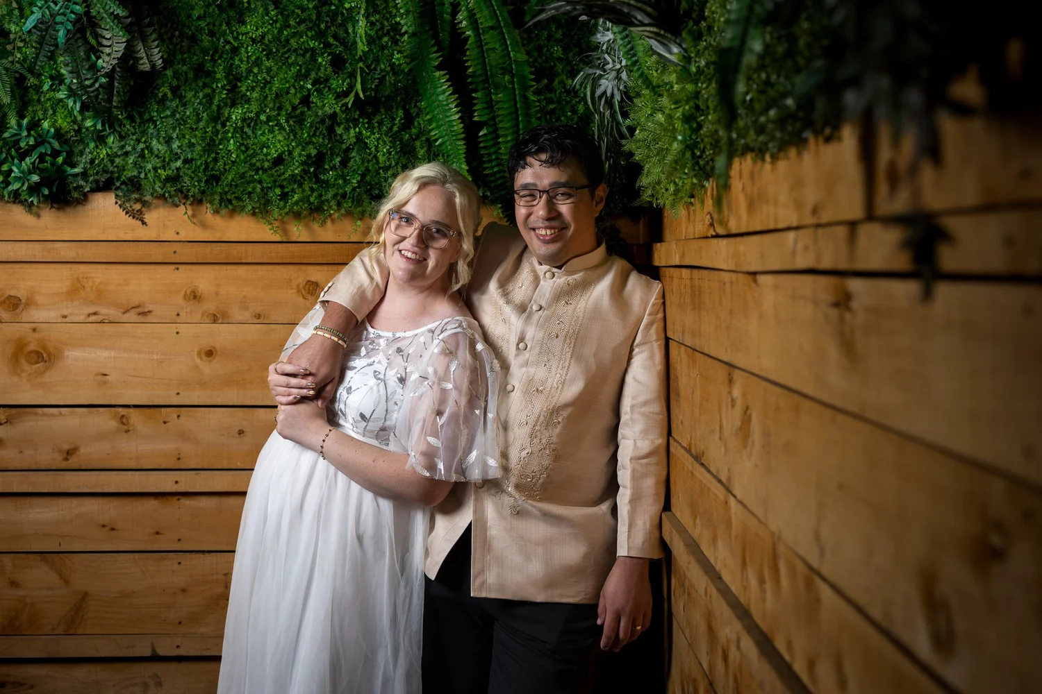 Kirstin and Justin against a timber and greenery wall