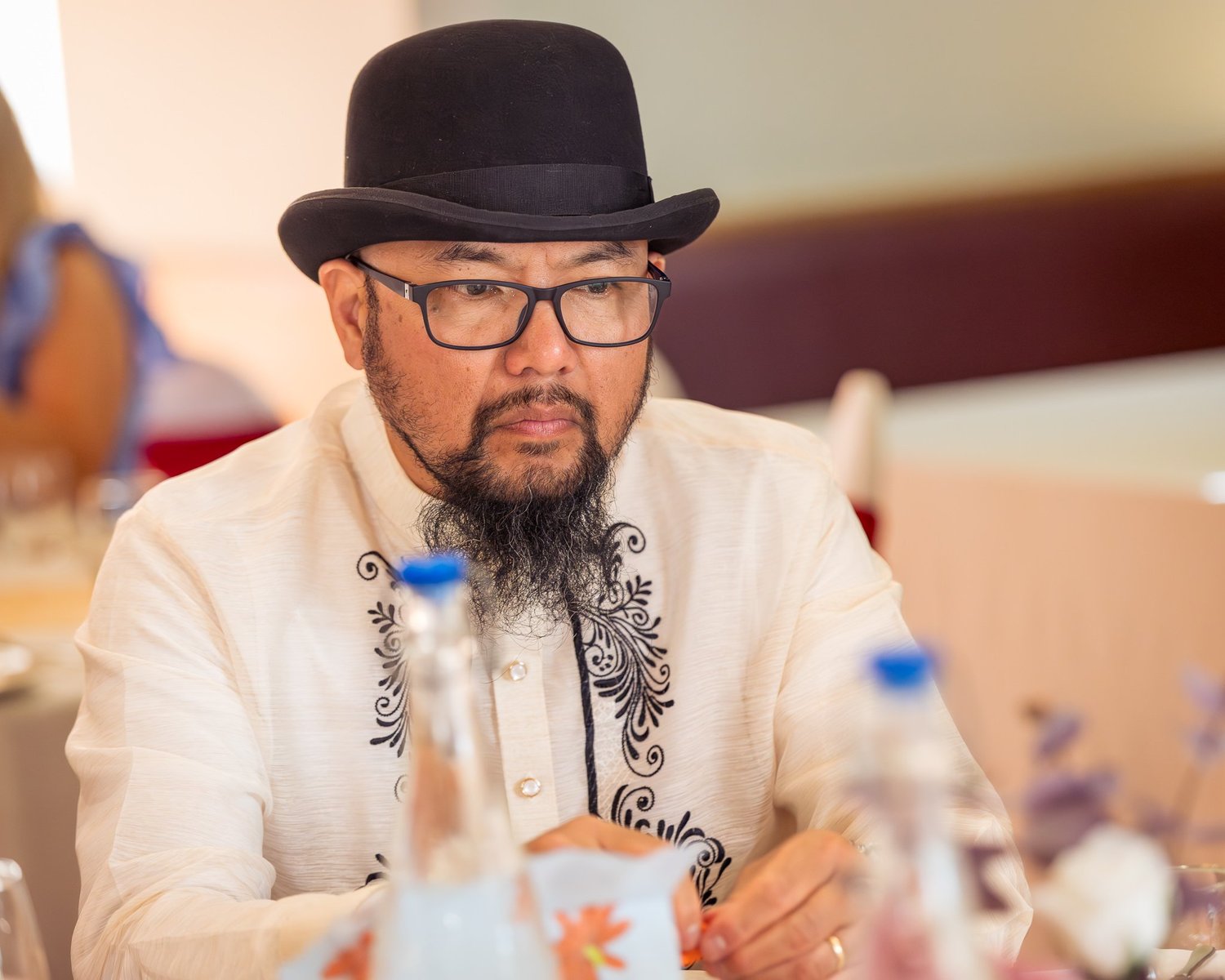 A guest in a bowler hat and glasses at his table