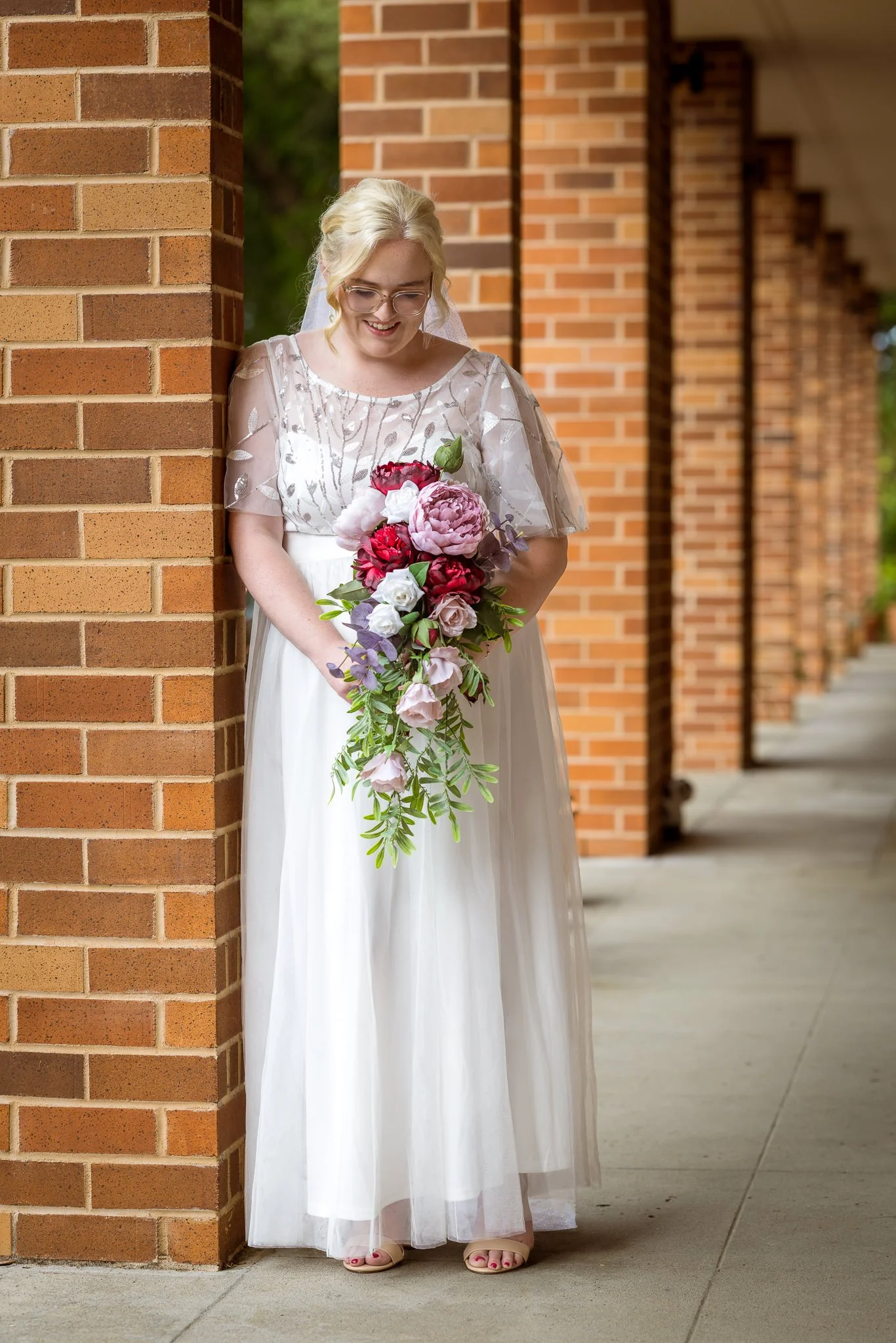 Kirstin with her bouquet in a brick colonnade