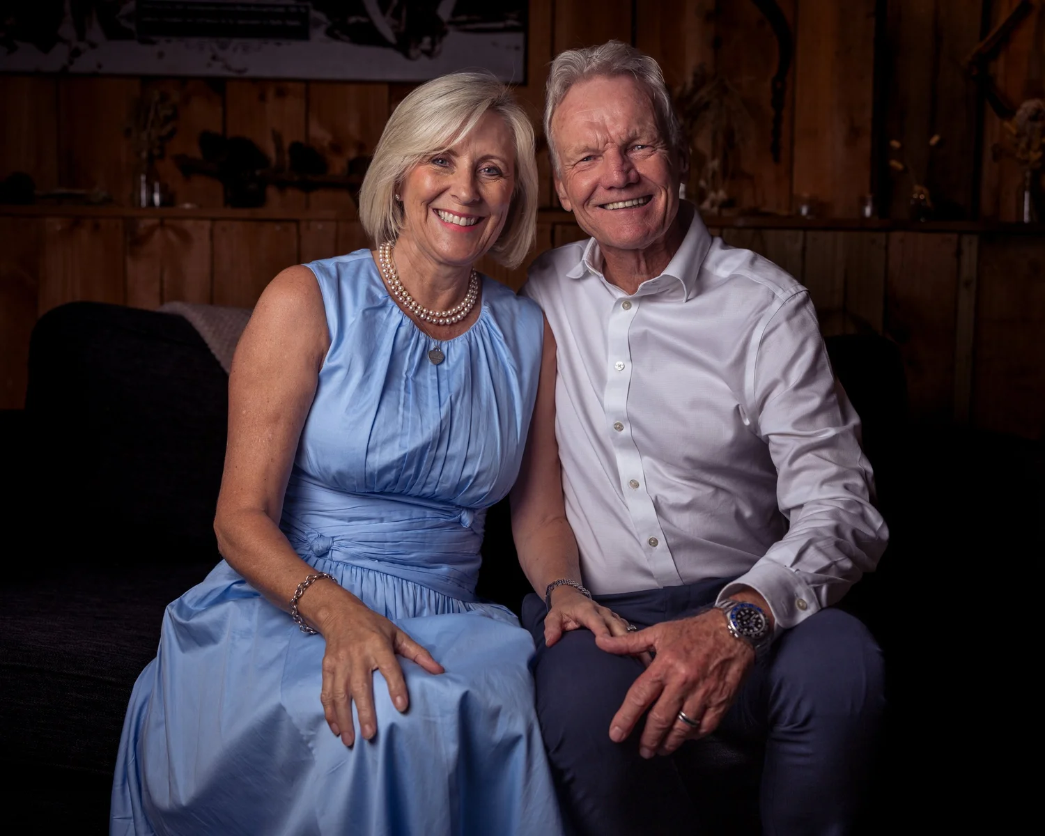 Two guests smile together on a dark sofa