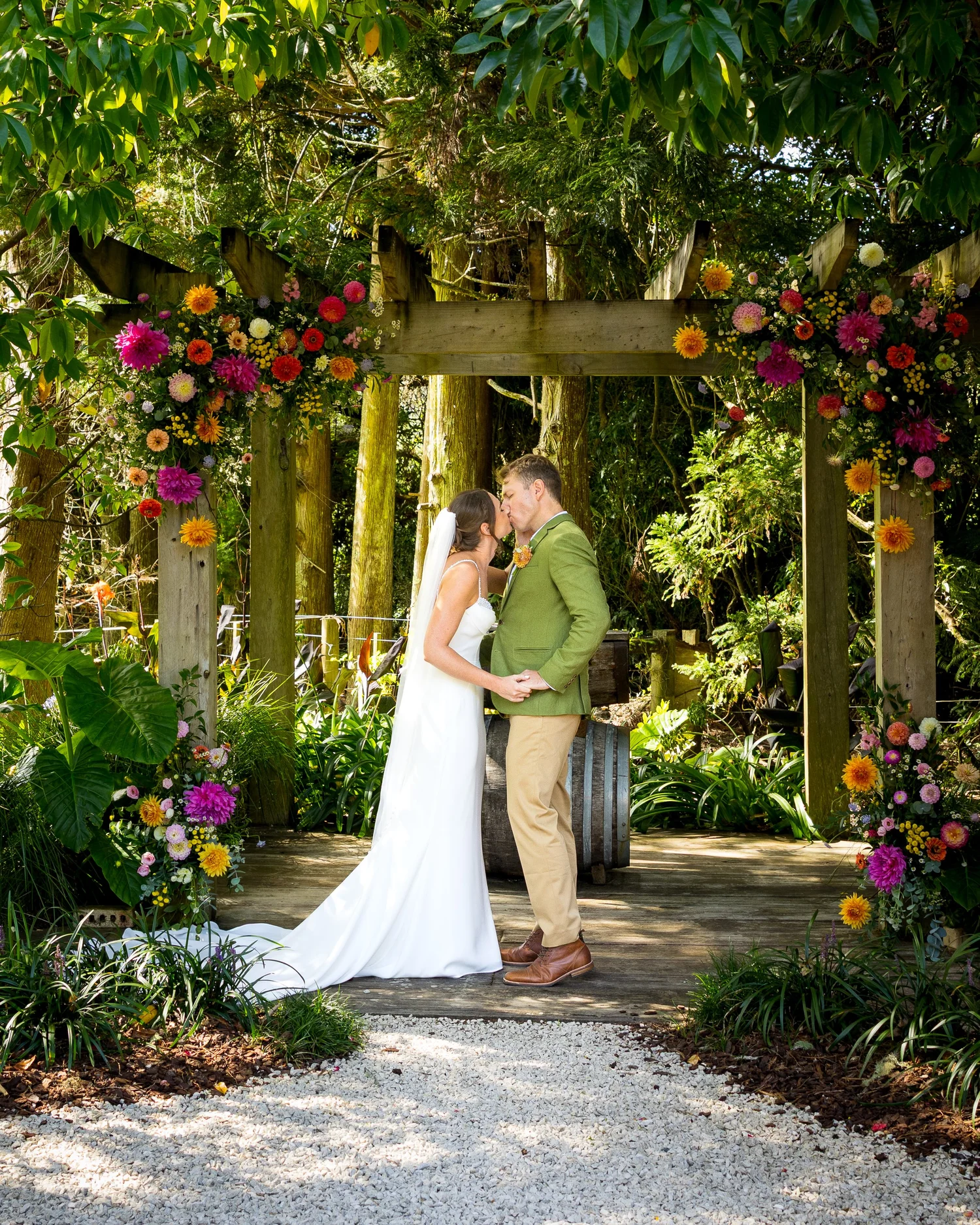 Jade and Ben under a flower-covered arch at Kumeu Valley Estate