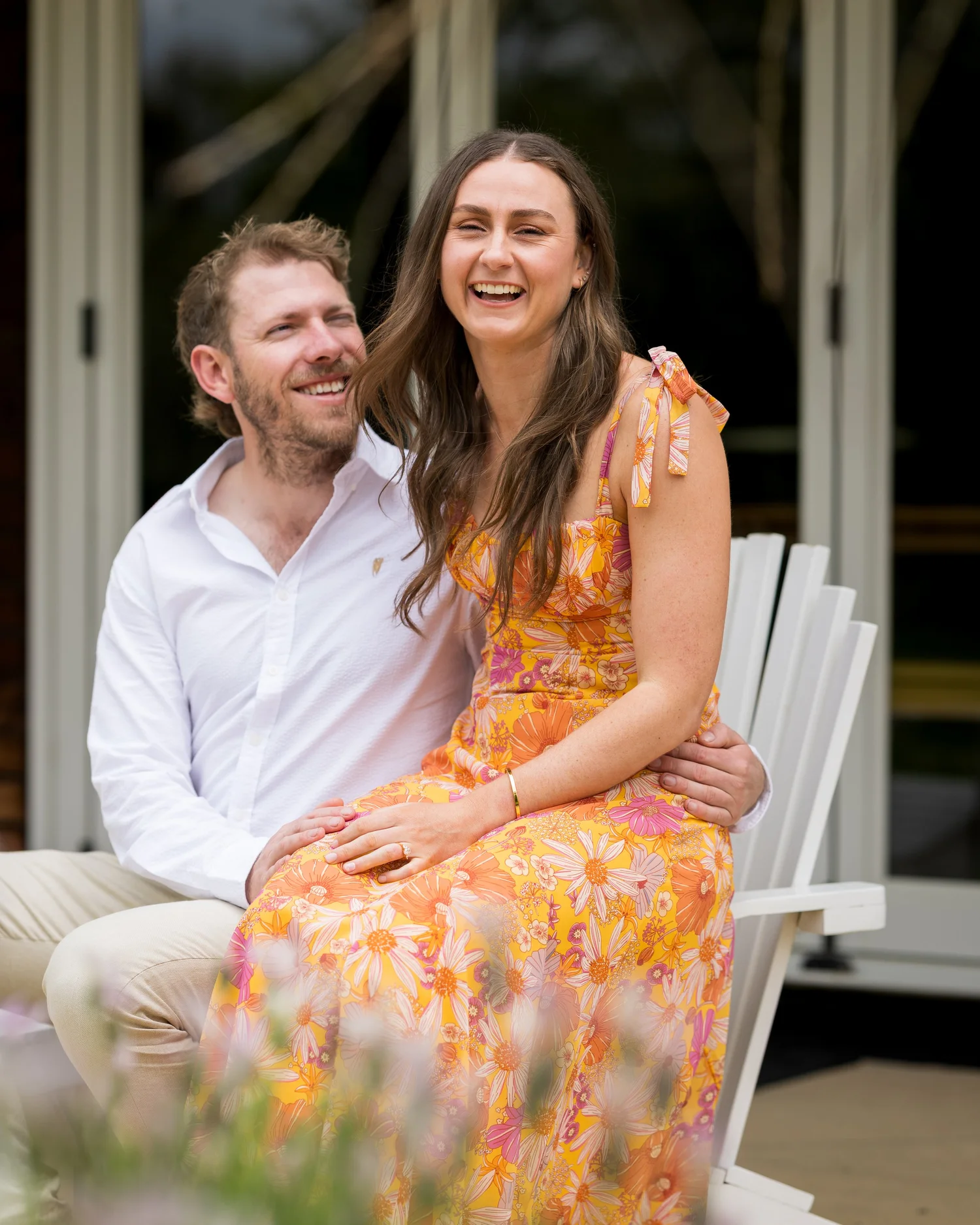 Jade sits on Ben's knee on a white garden chair