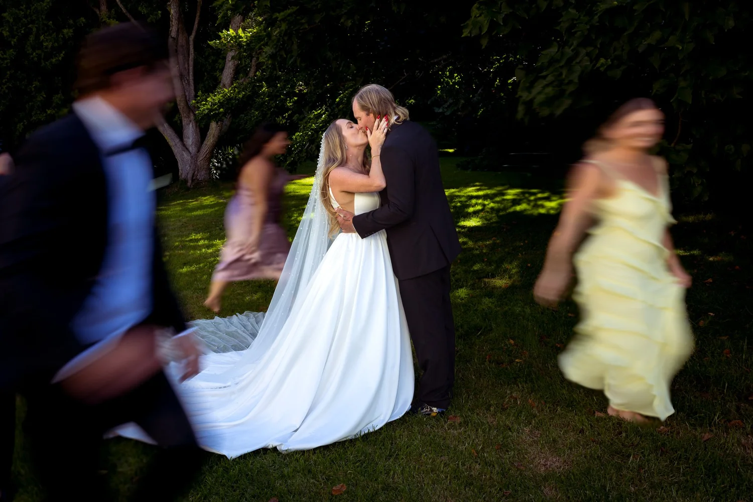Chanel and Latham kiss on the lawn as guests pass by