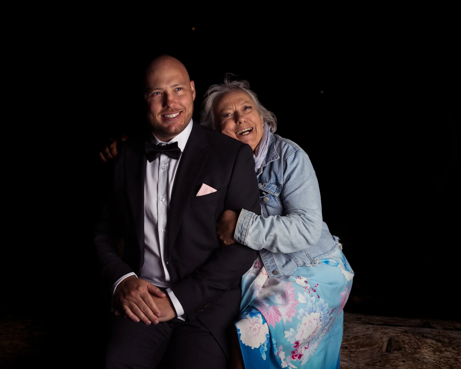 Two guests pose together on a stone wall in the dark