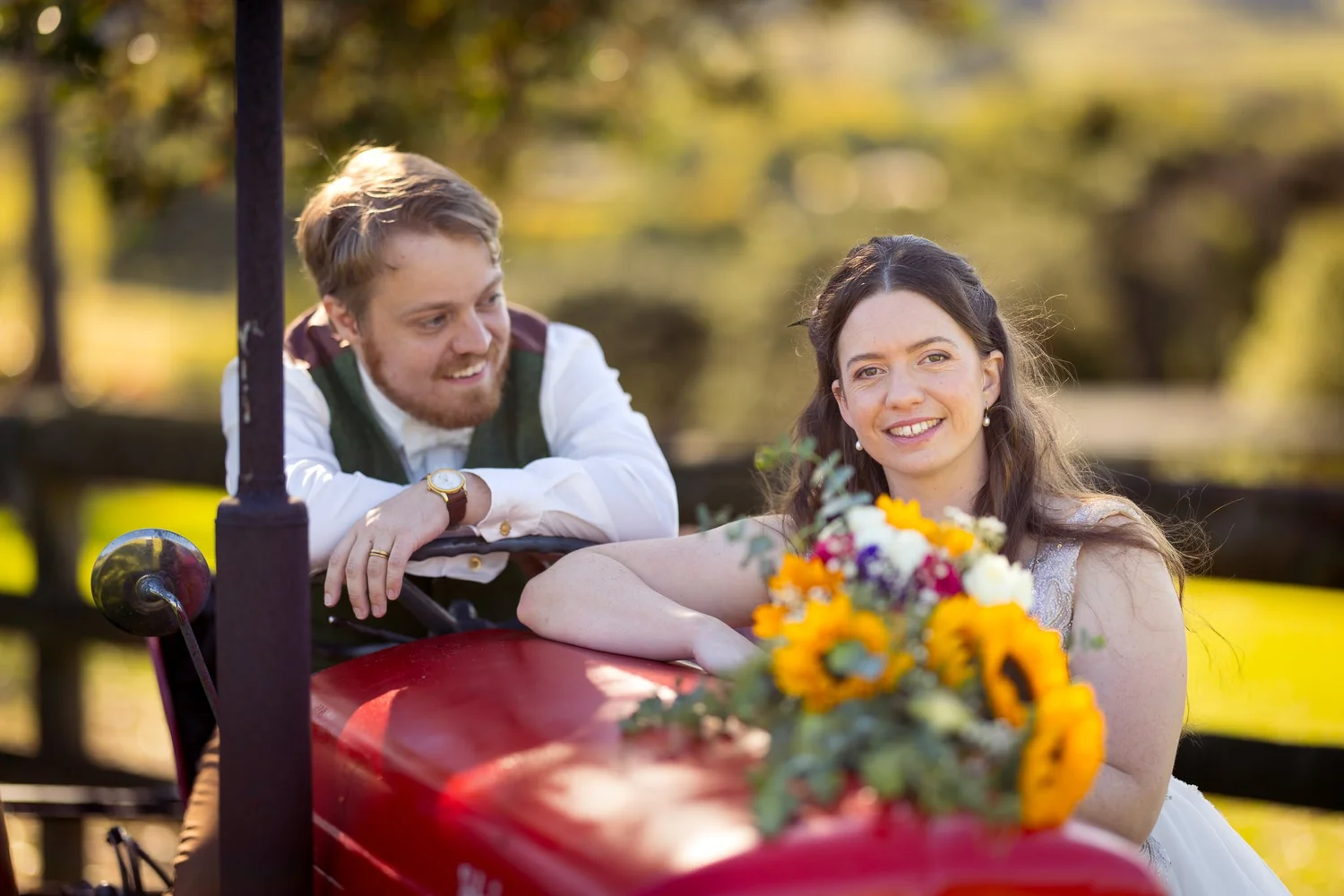 Mikaela and Dylan lean on a red vintage tractor