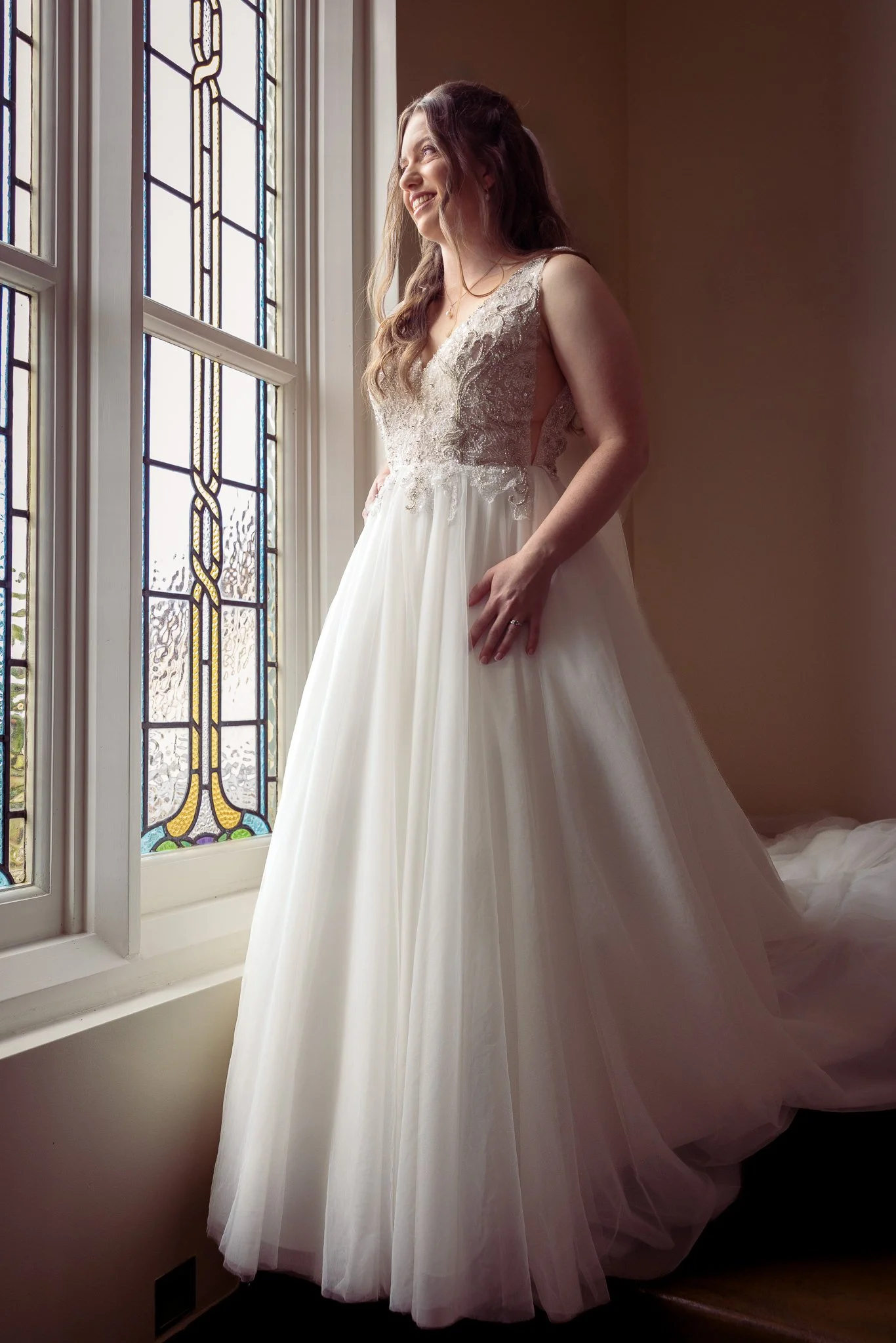 Mikaela in her gown beside a leadlight window