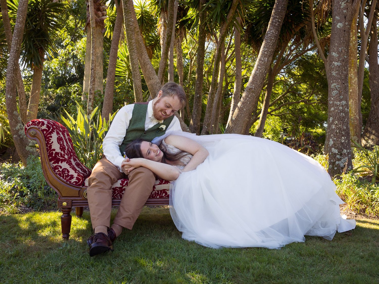 Mikaela and Dylan relax on a red velvet chaise in the garden