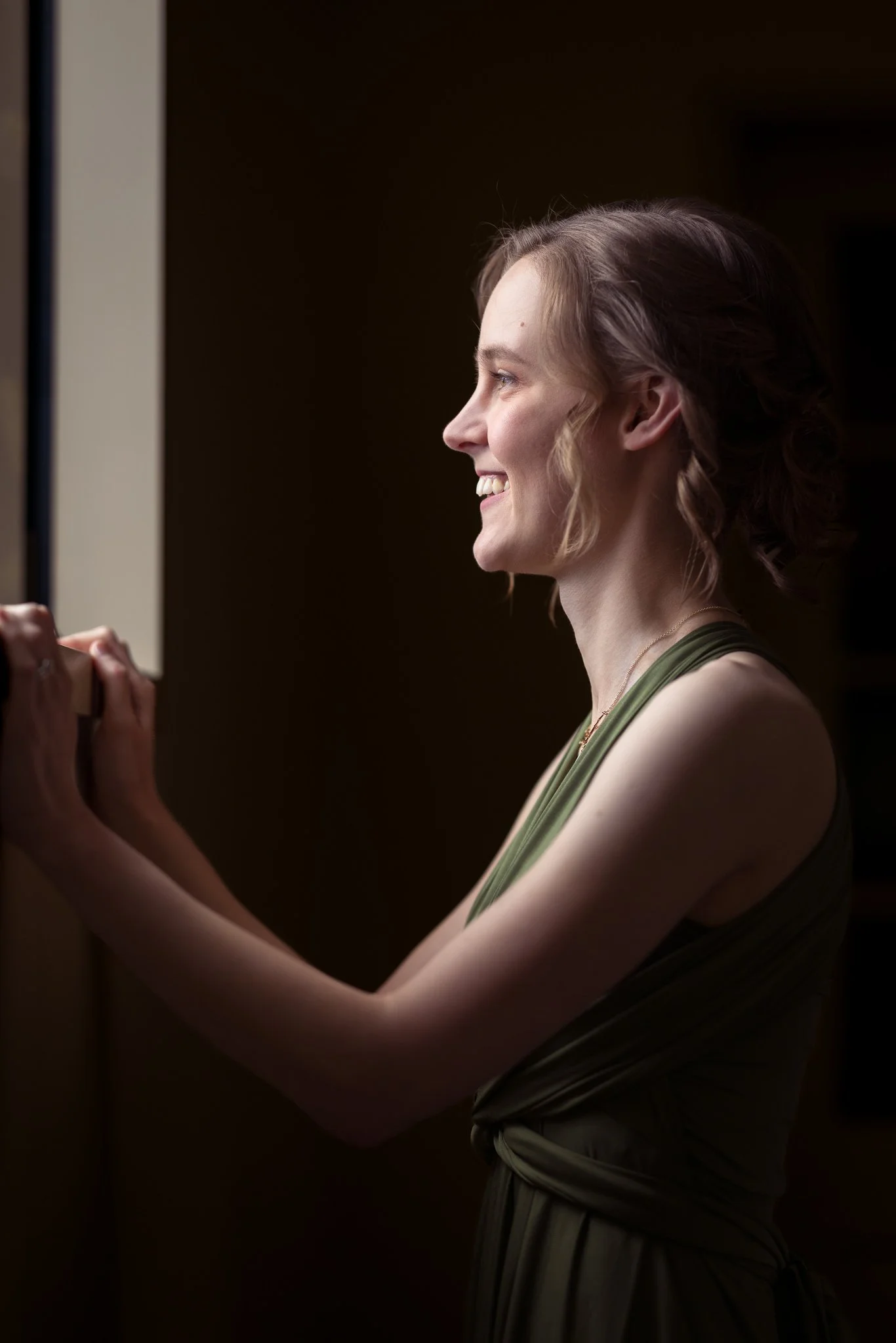 A bridesmaid in green looks out of a window