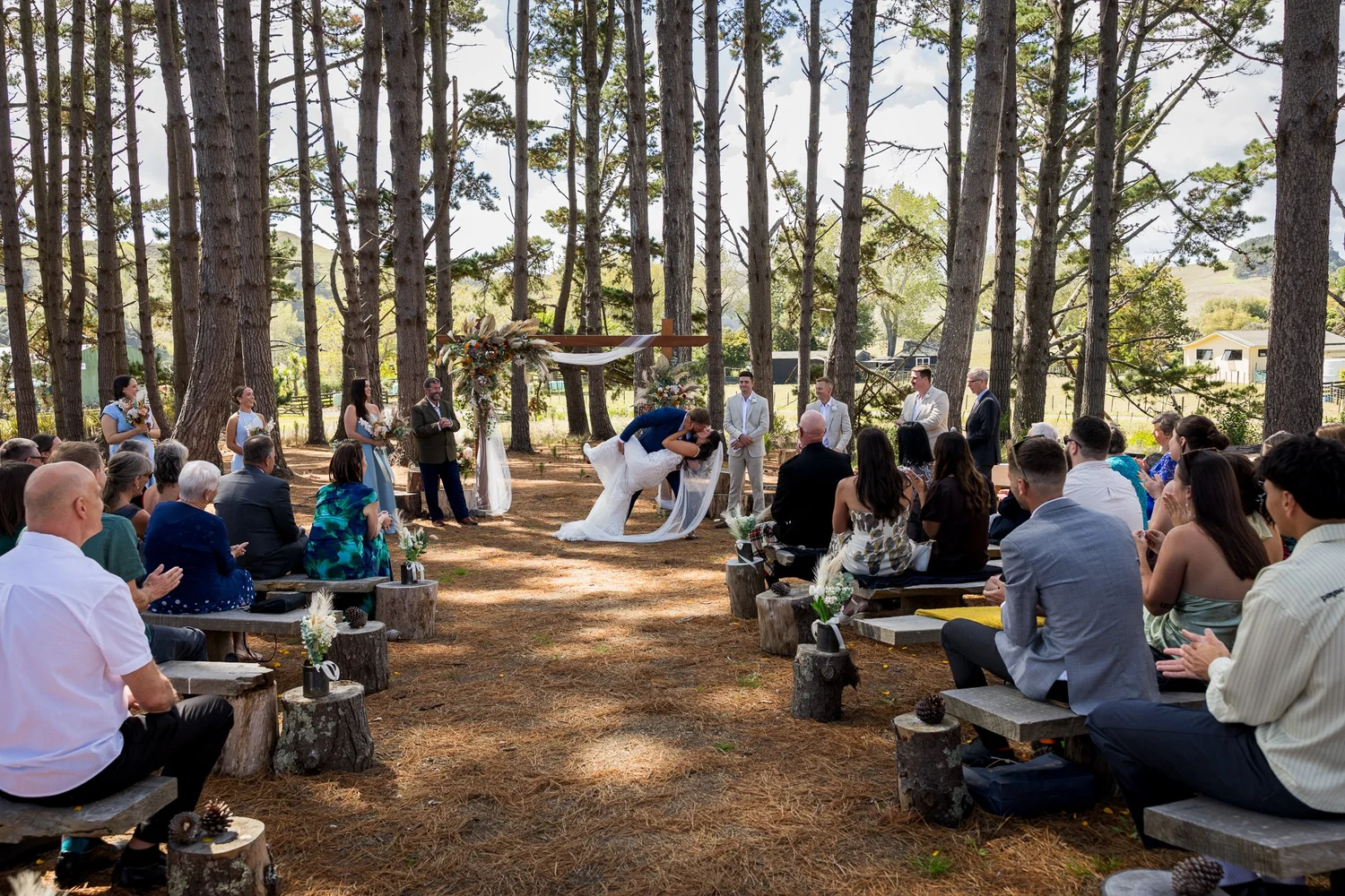 Guests seated among the pine trees at The Barn Waimauku