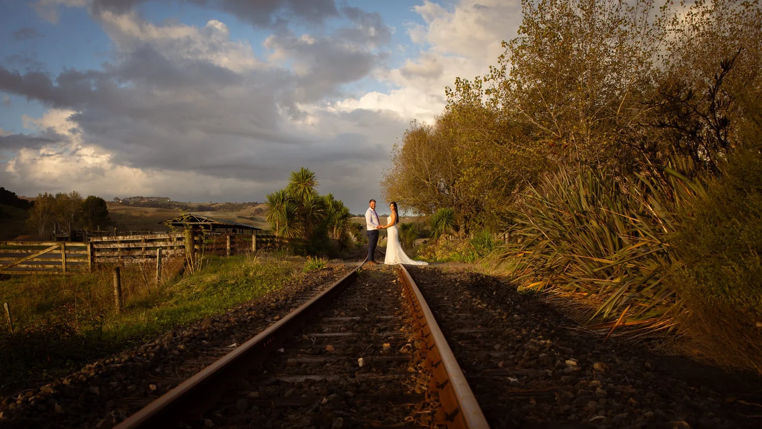 Tay walks along a railway line under a dramatic sky