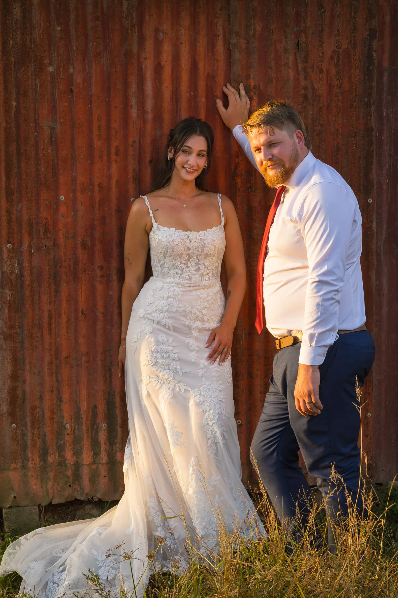 Tay and Jesse against a rusty red corrugated wall