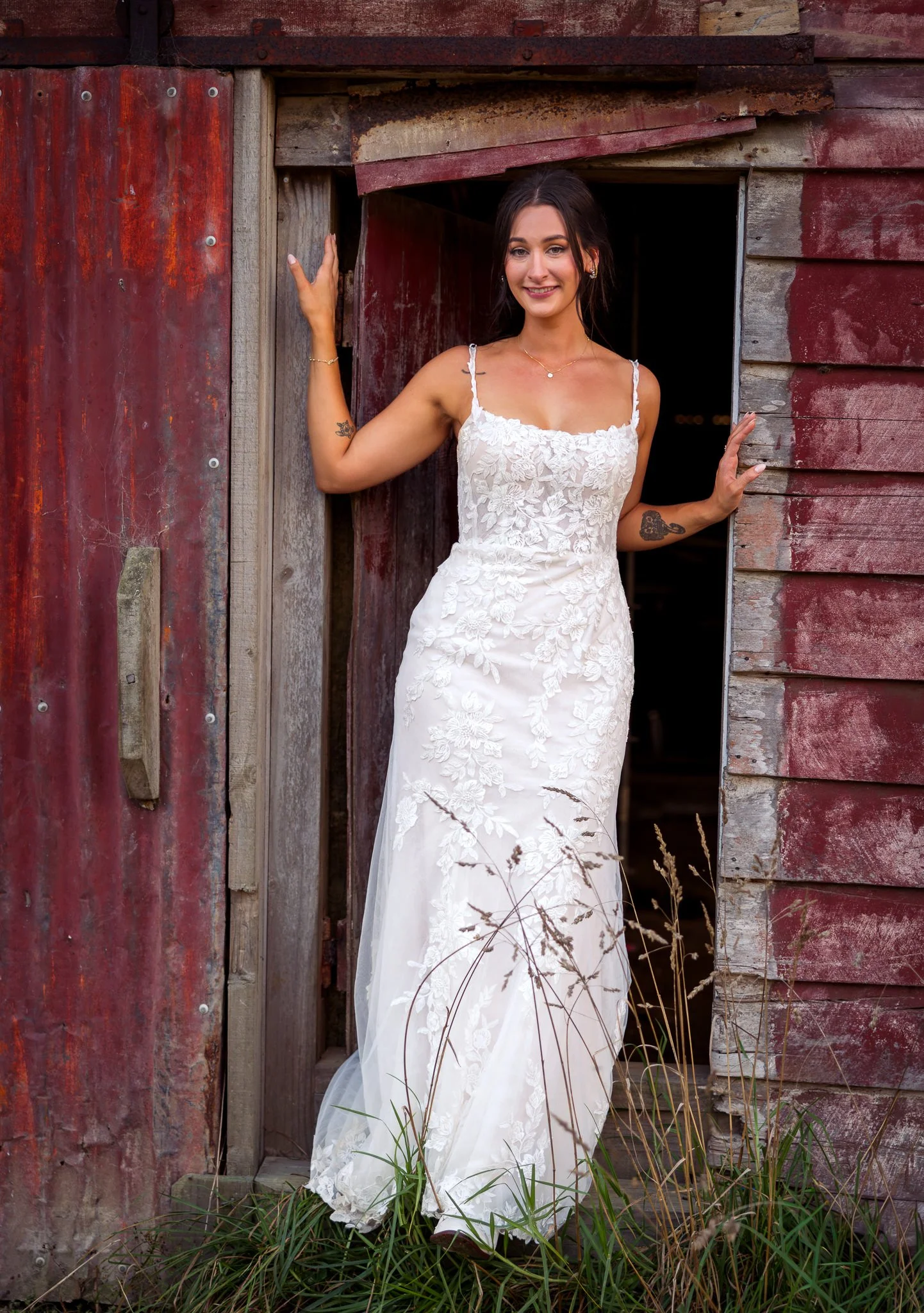 Tay in her gown in the doorway of a red barn