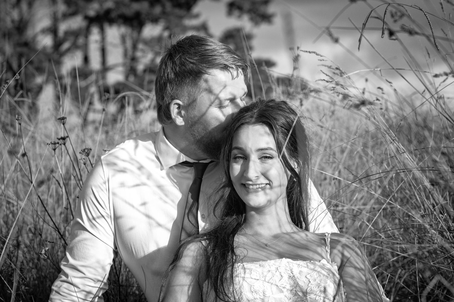 Black and white photo of Tay and Jesse sitting in long grass