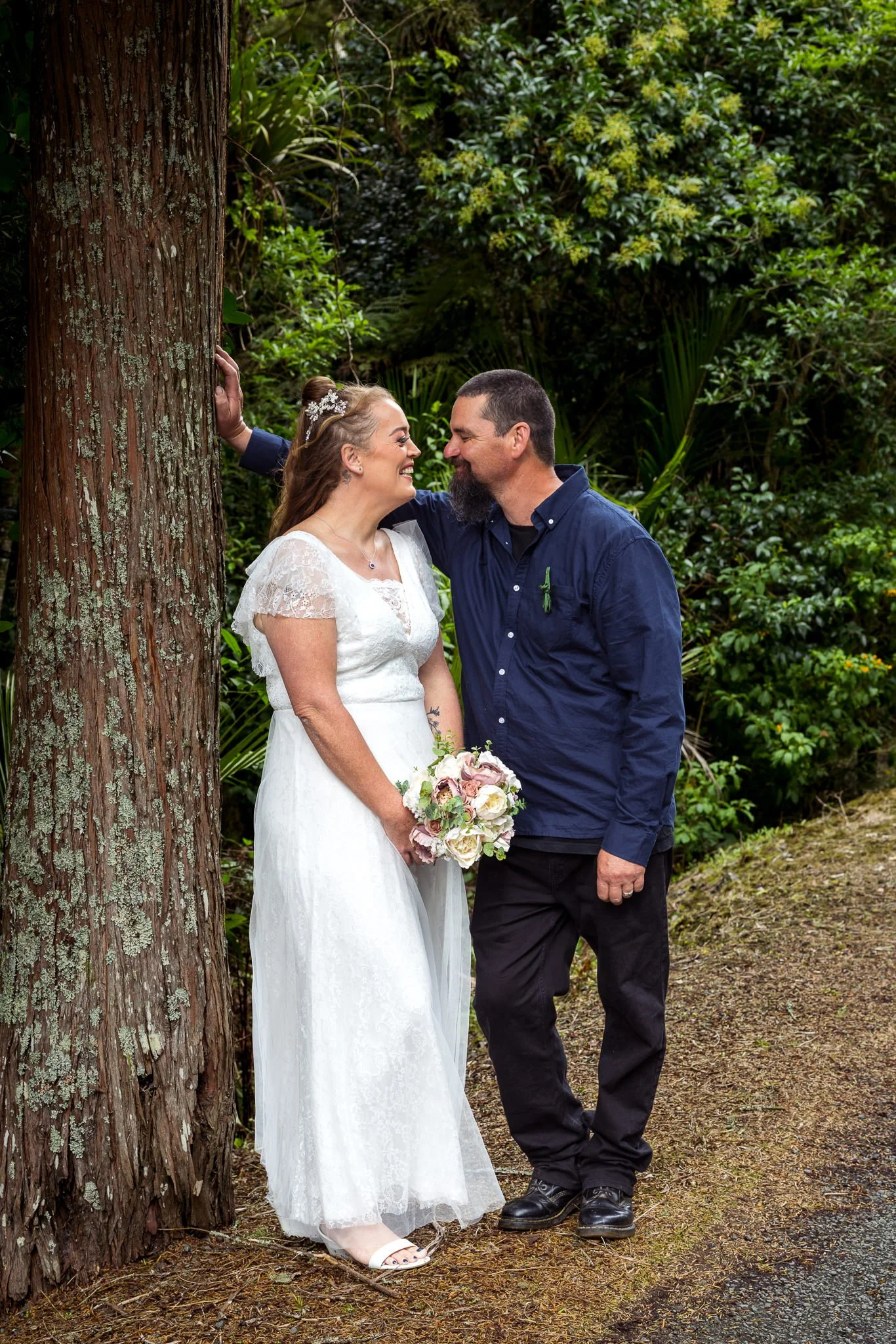 Julia and Alistair beside a tall tree in Maungaturoto