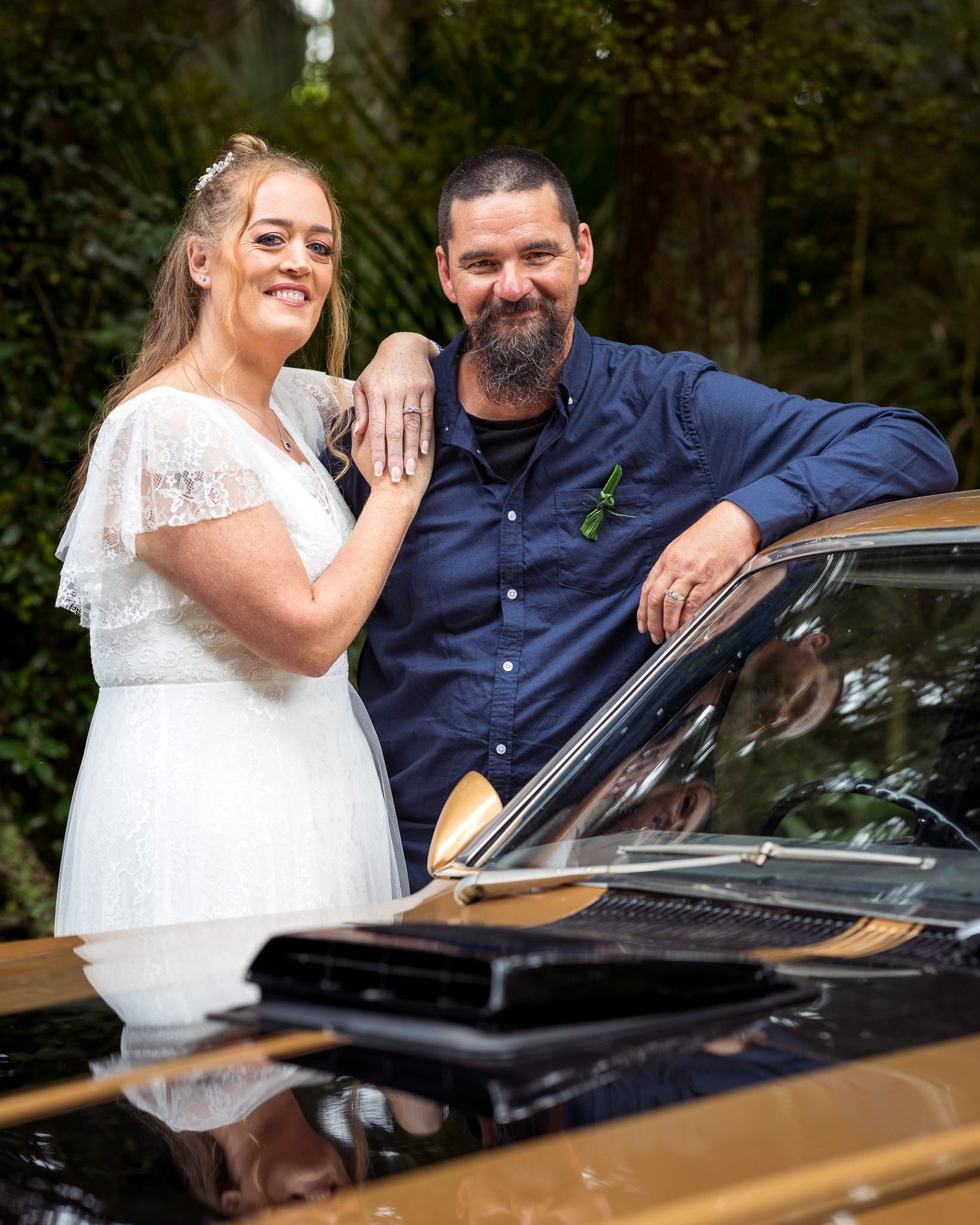 Julia and Alistair pose beside a vintage muscle car
