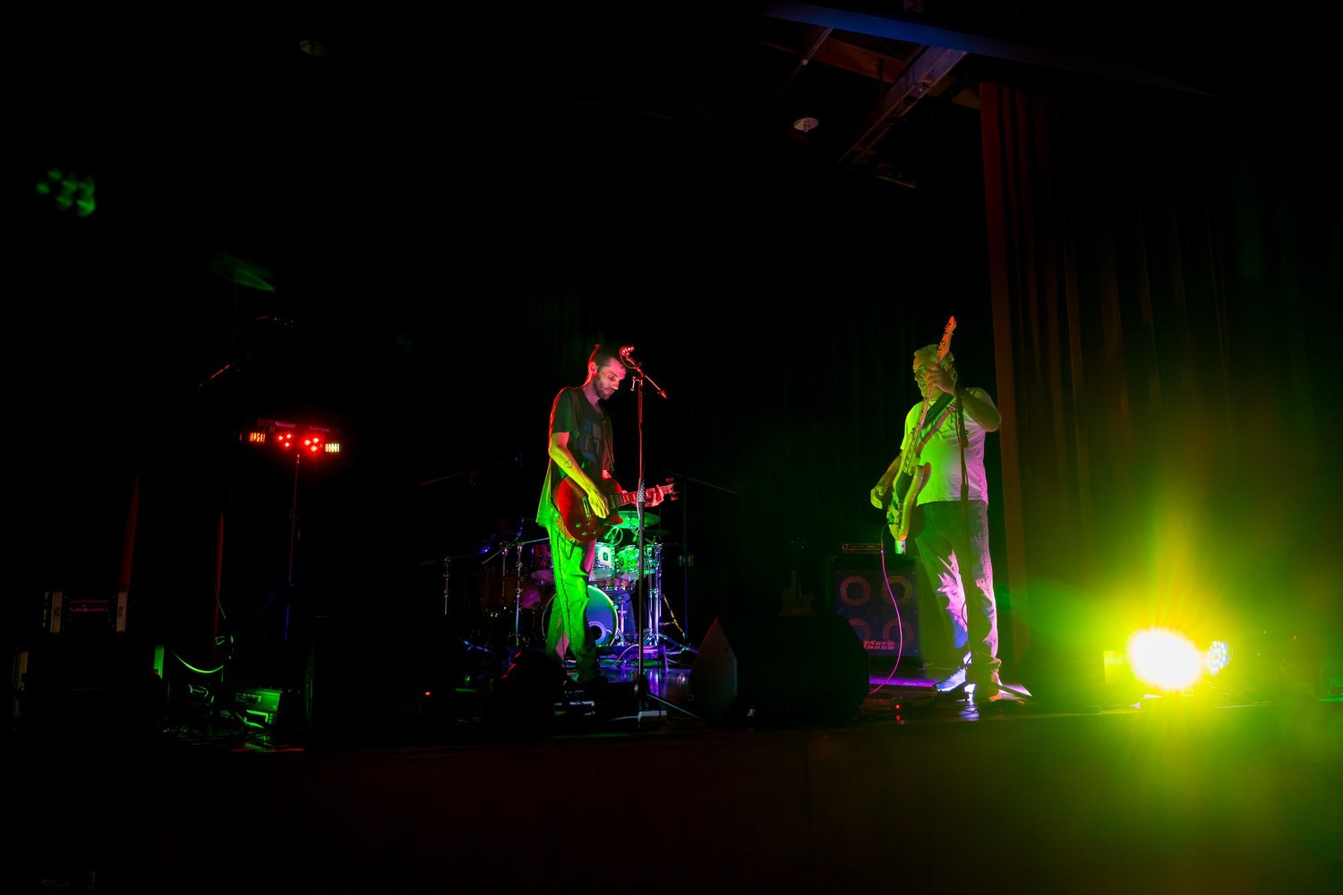 The band plays under green stage lights in the hall