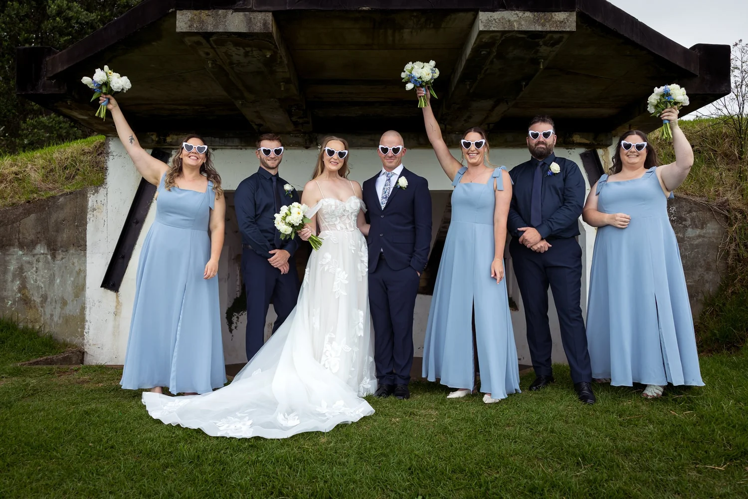 The bridal party cheers with bouquets raised
