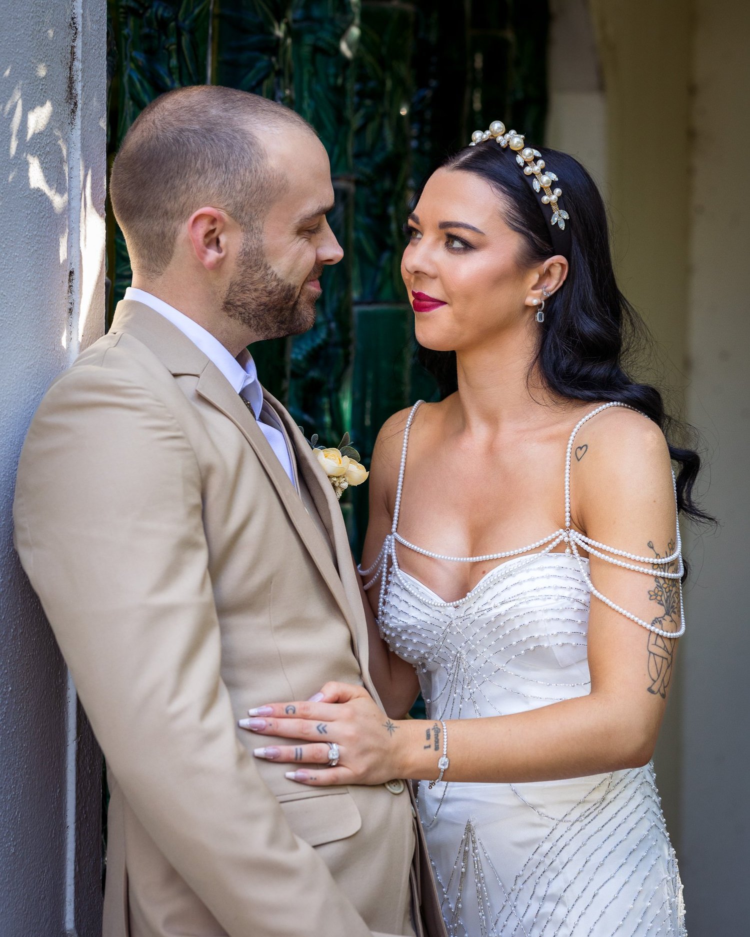 Emma and Corey face each other beside a garden doorway