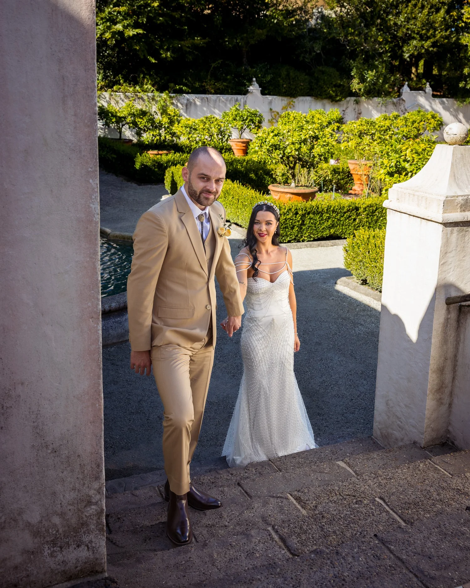 Emma and Corey walk hand in hand through an Italian-style garden