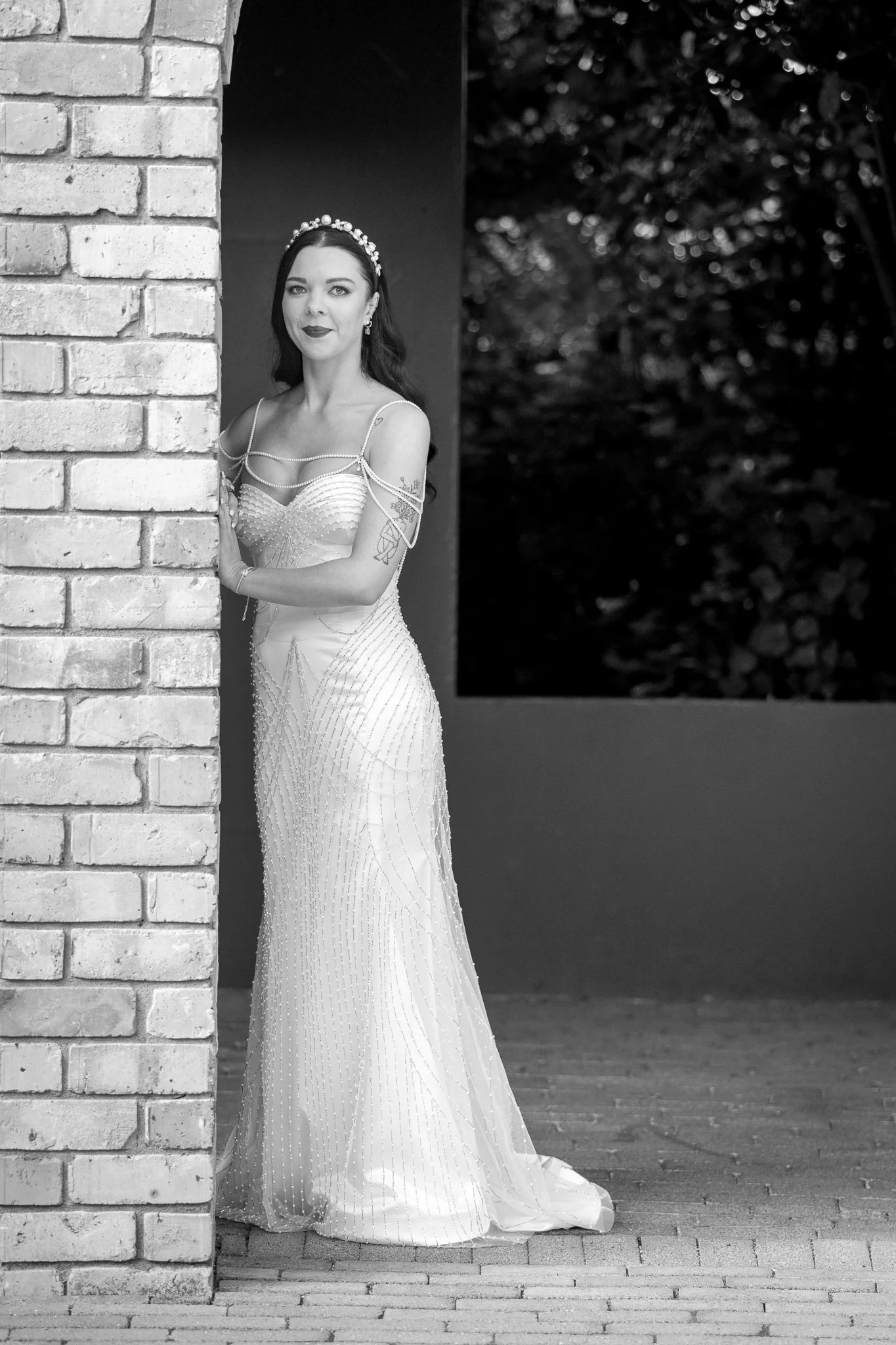 Black and white photo of Emma beside a brick column