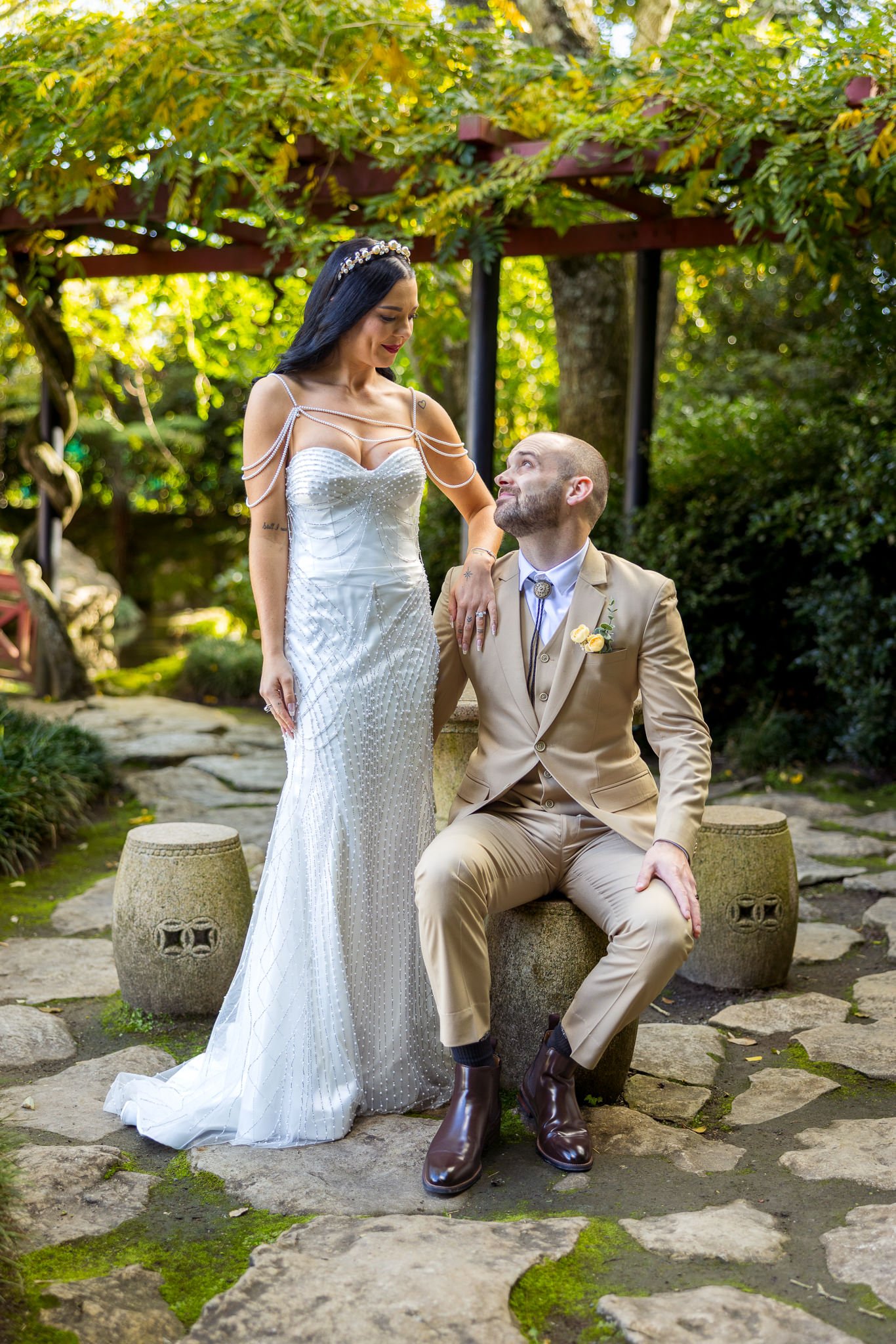 Emma stands beside Corey seated on a garden stool