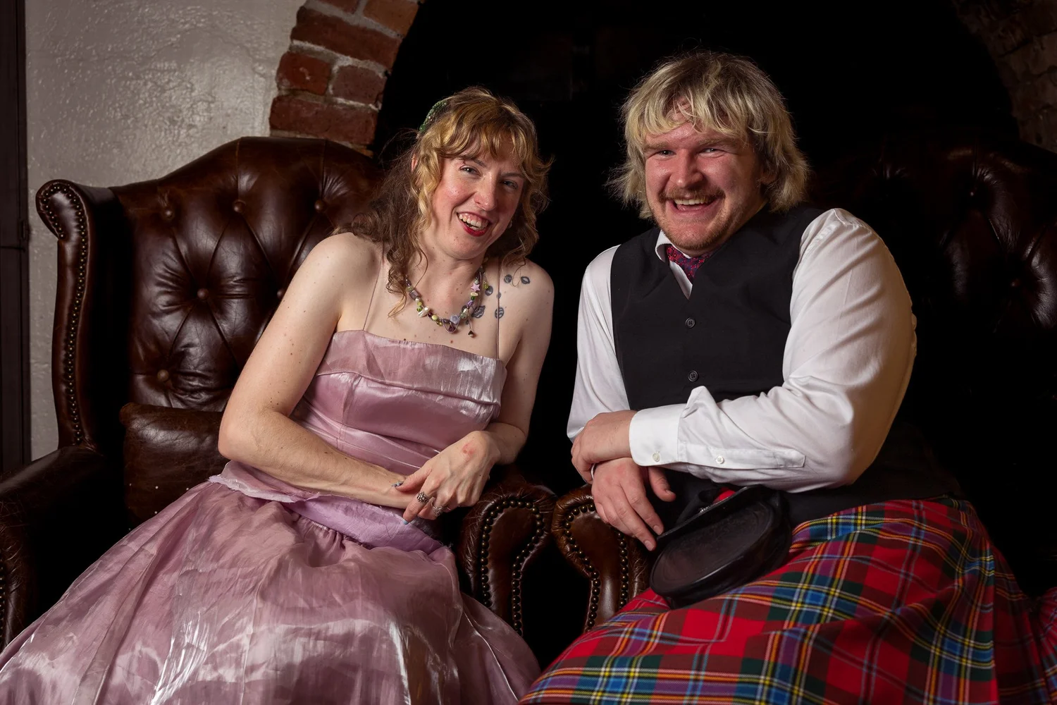 Two guests in tartan and pink on a leather sofa