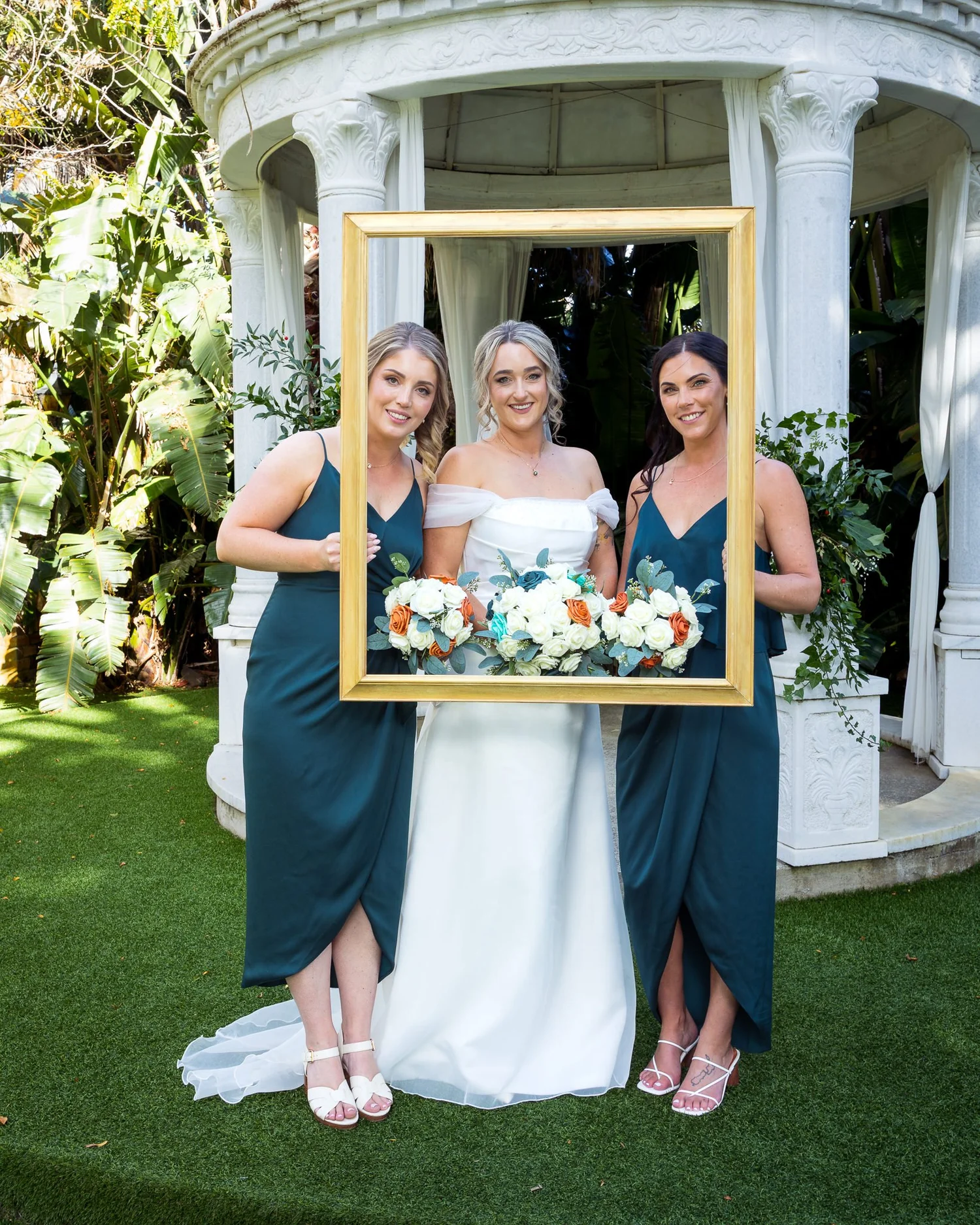 Felicity and her bridesmaids pose with a gold frame by the rotunda